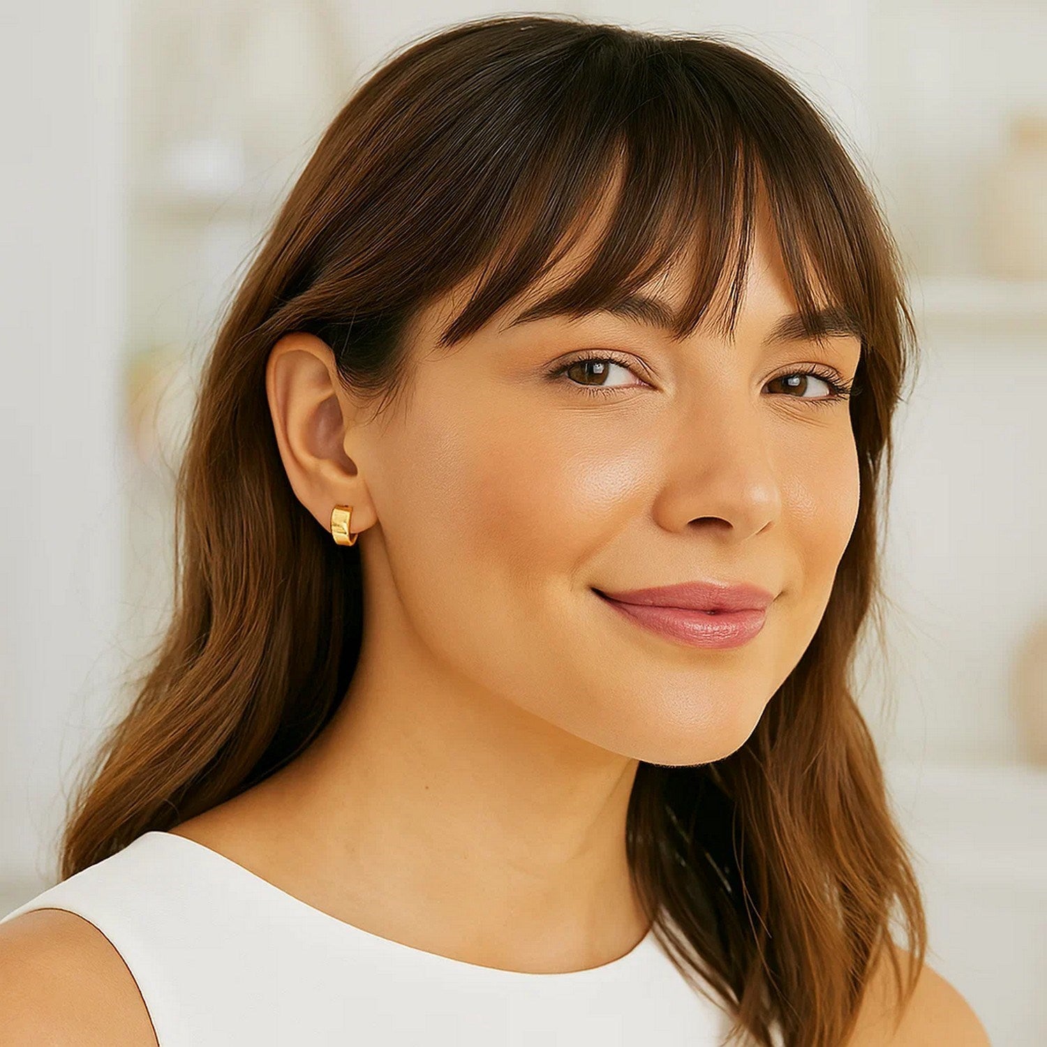 14k yellow gold snuggable hoop earrings on a woman.