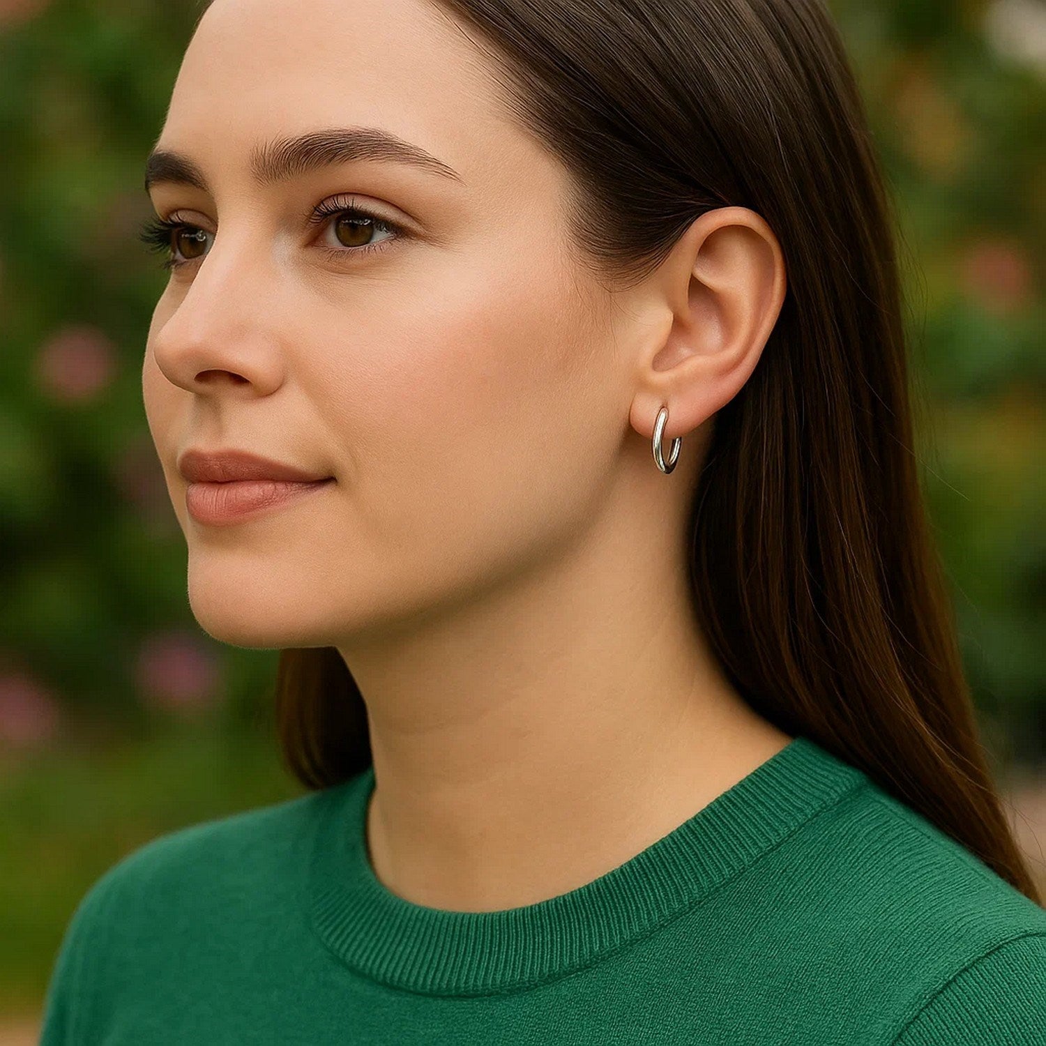 14k white gold petite polished round hoop earrings on a woman's ear.