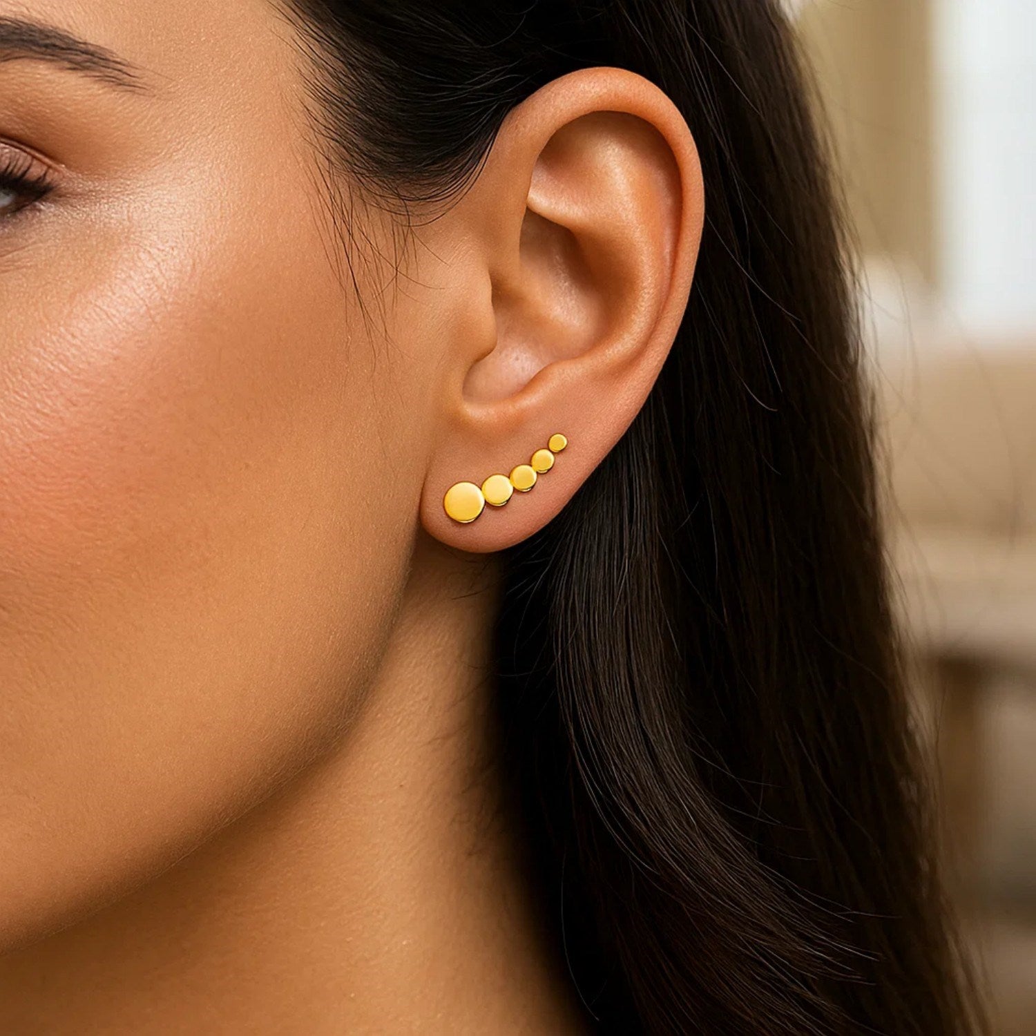 14k yellow gold graduated circles climber post earrings on a woman's ear.