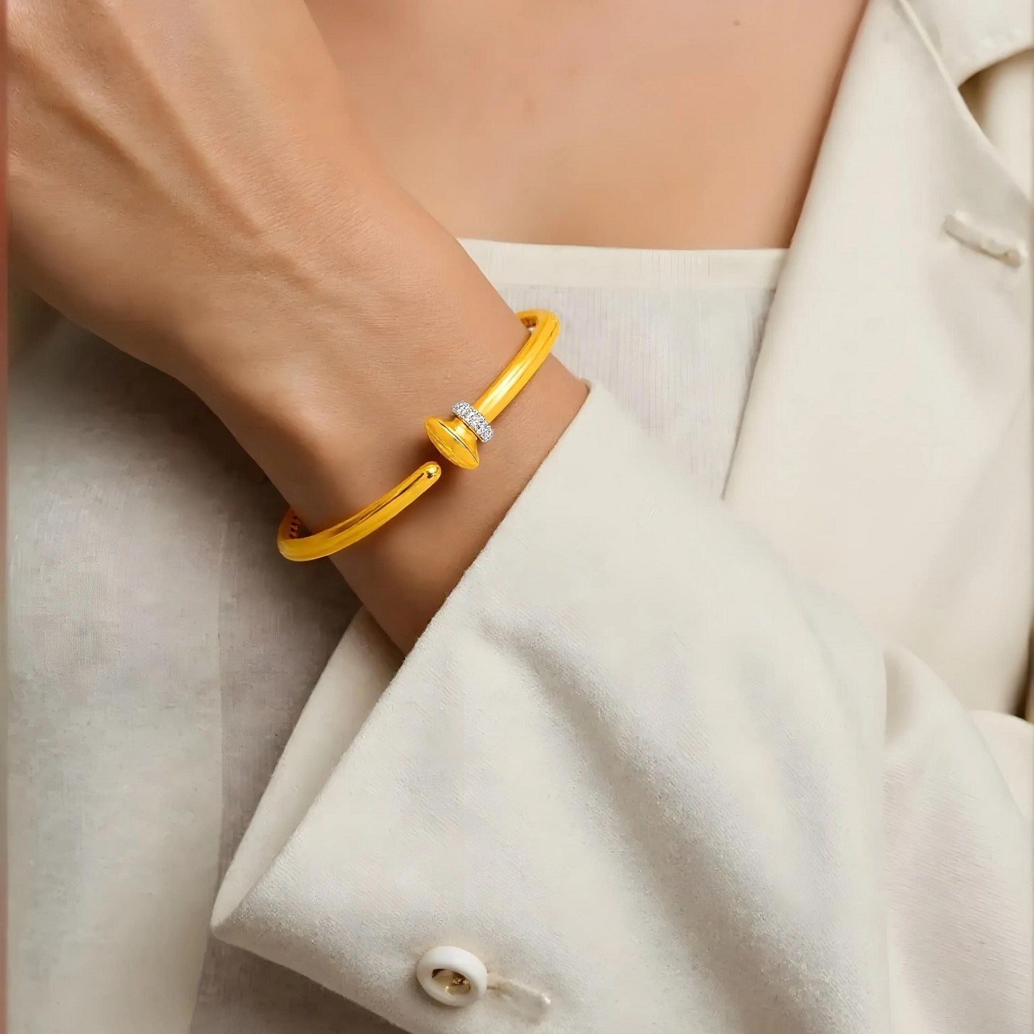 14k yellow gold hinged bangle bracelet with diamonds on a woman's wrist.