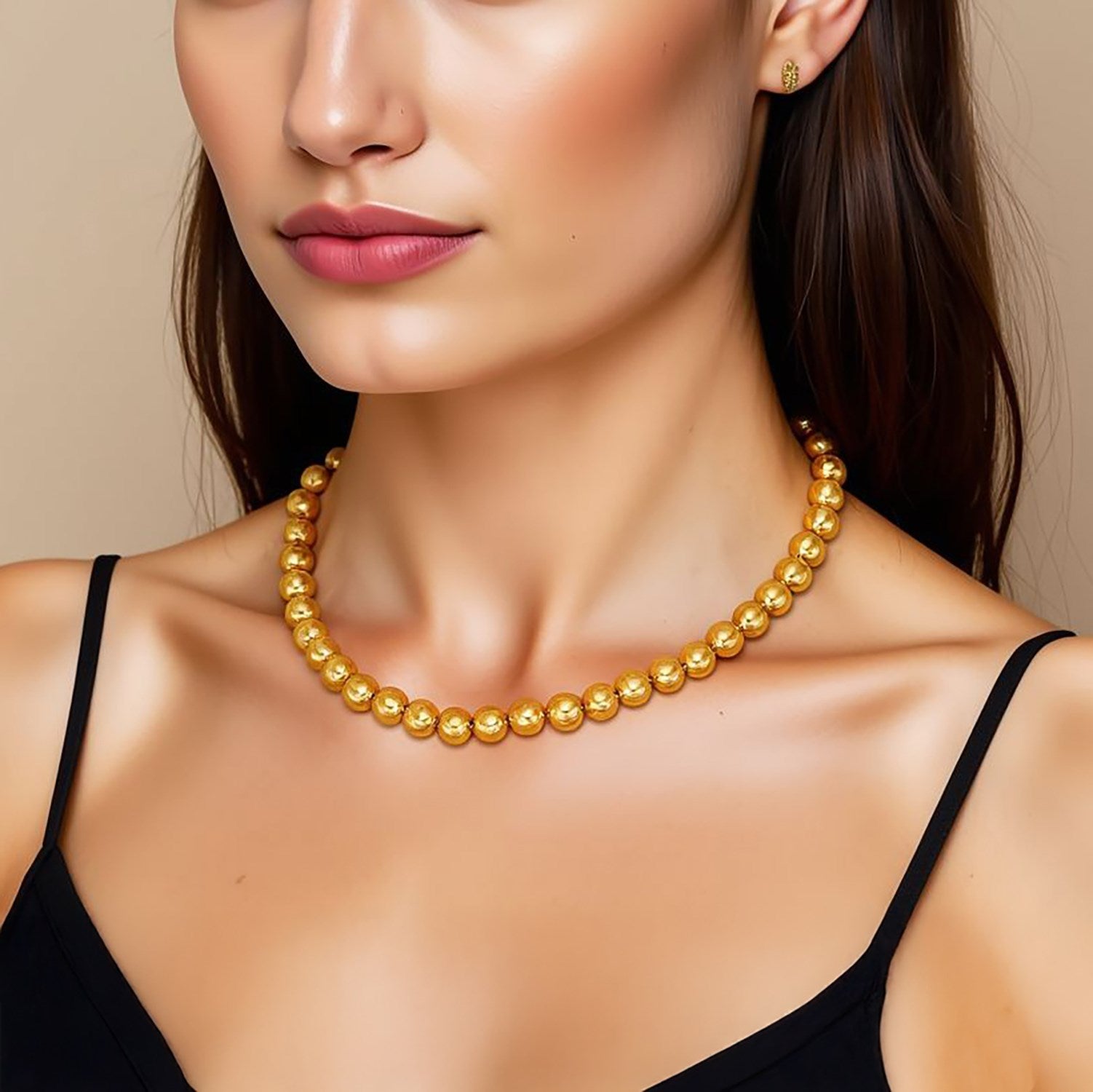 A woman wears a 14k yellow gold bead chain necklace and matching stud earrings.