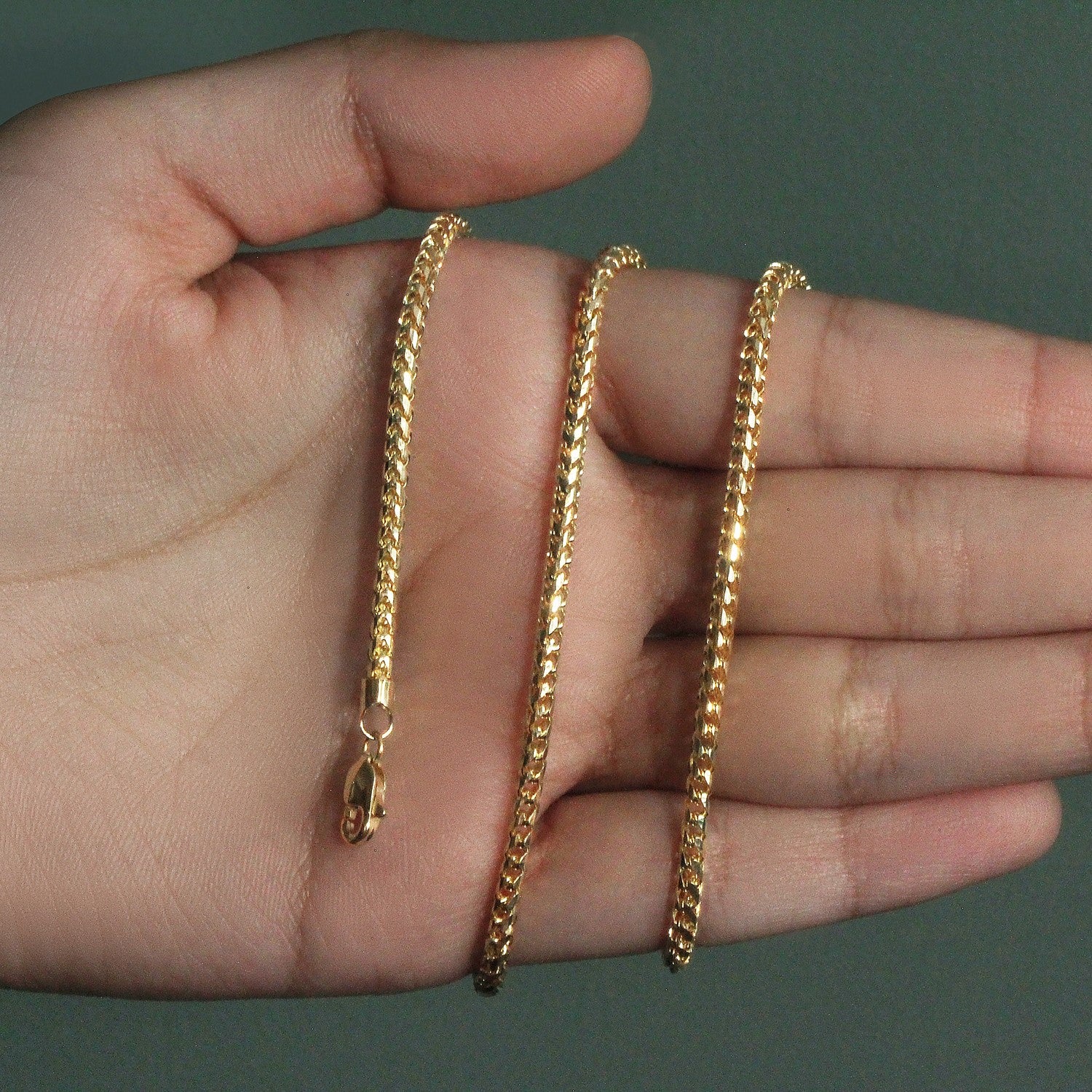 14k yellow gold diamond cut round Franco chain held in an open hand.