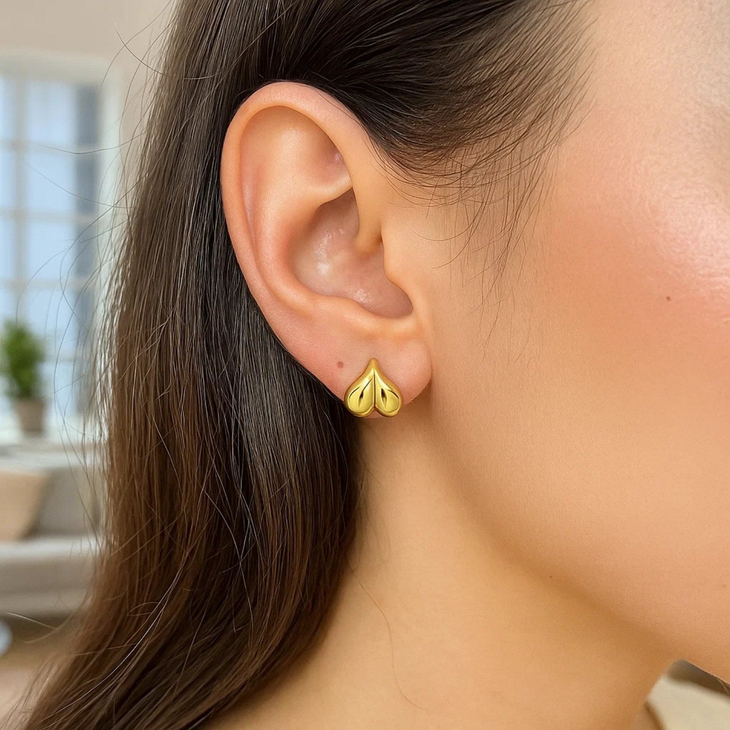 14K yellow gold puffed bubble heart stud earring on a woman's ear.