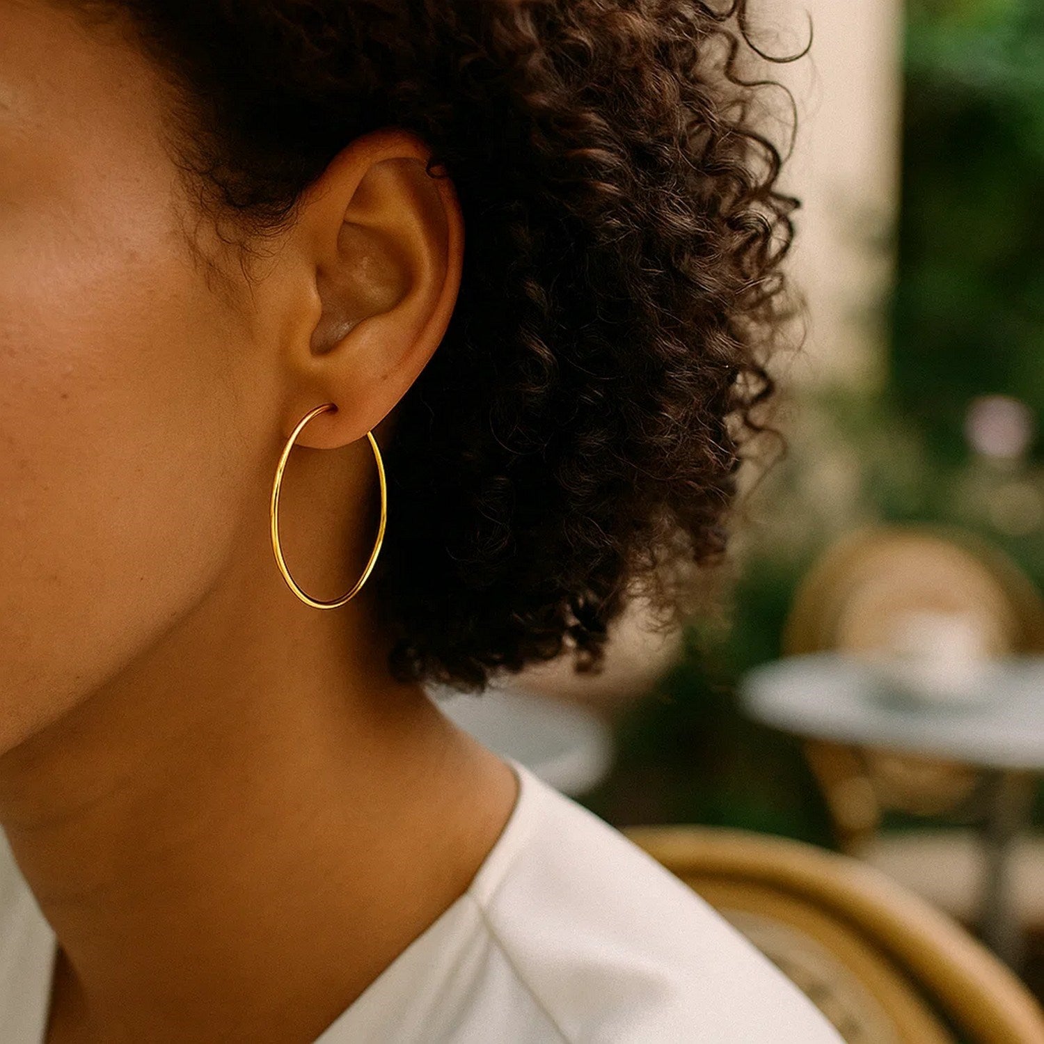 14K yellow gold endless hoop earrings on a person's ear.