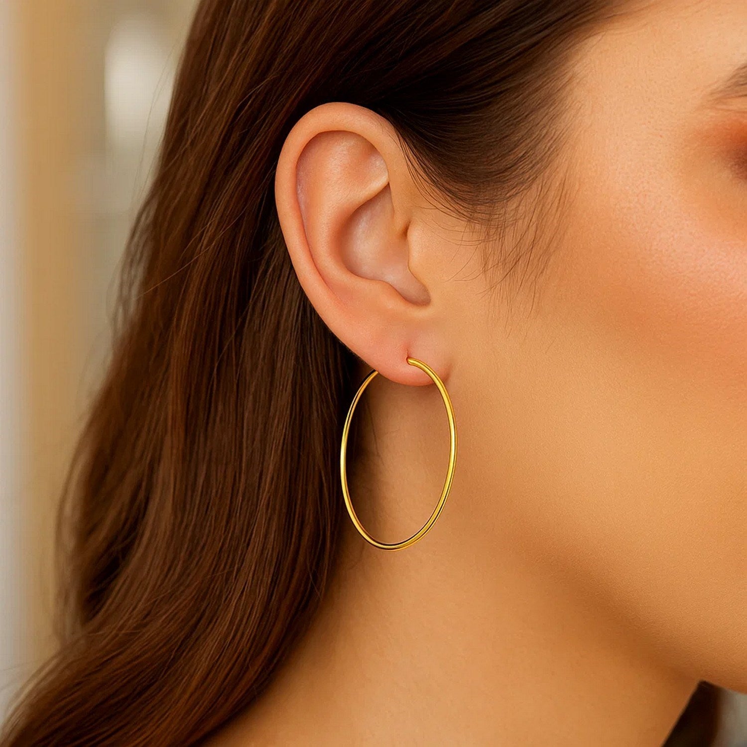A woman wears a single 14K yellow gold endless hoop earring.