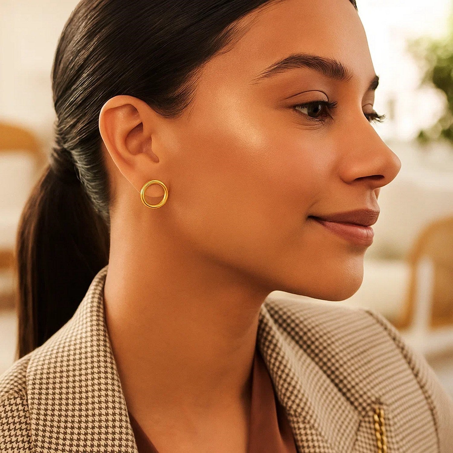 Open circle post earrings in 14k yellow gold on a woman's ear.