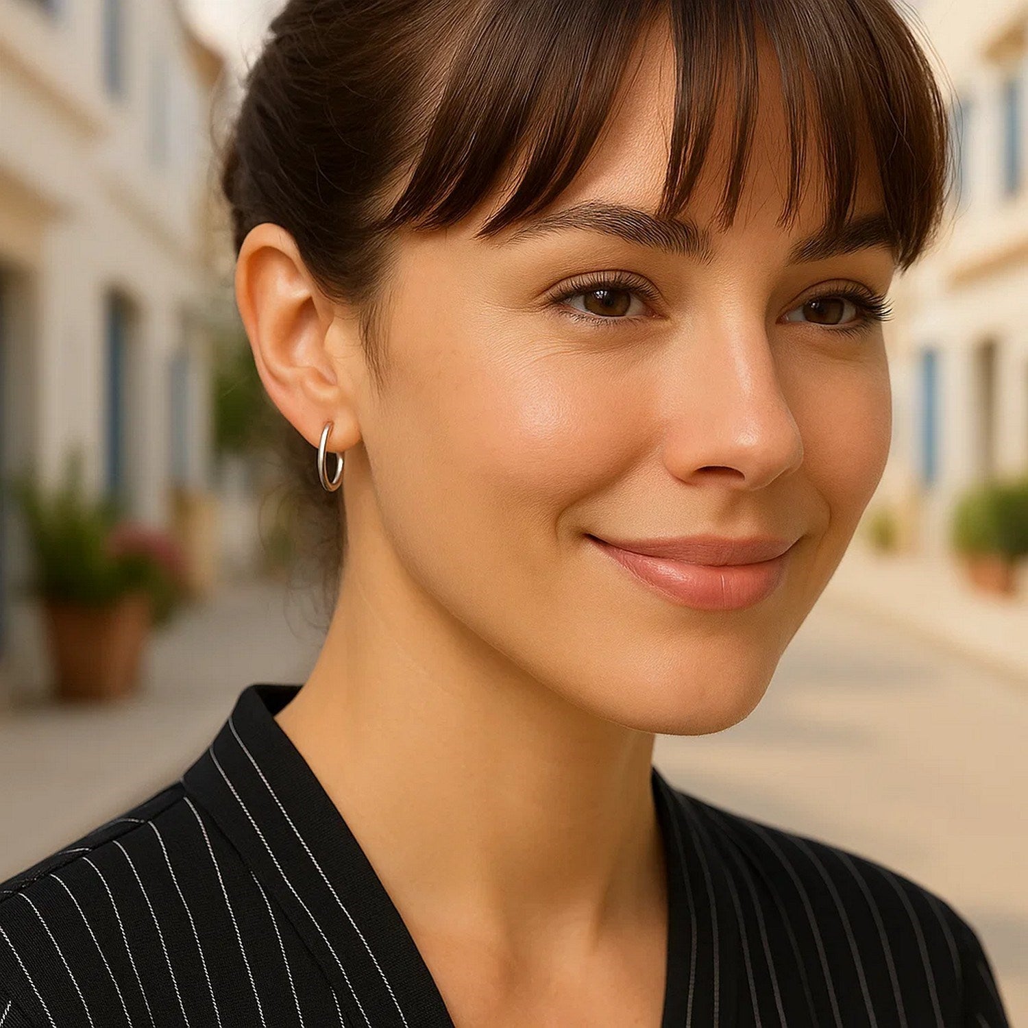 Polished sterling silver hoop earrings are worn on a woman's ear.
