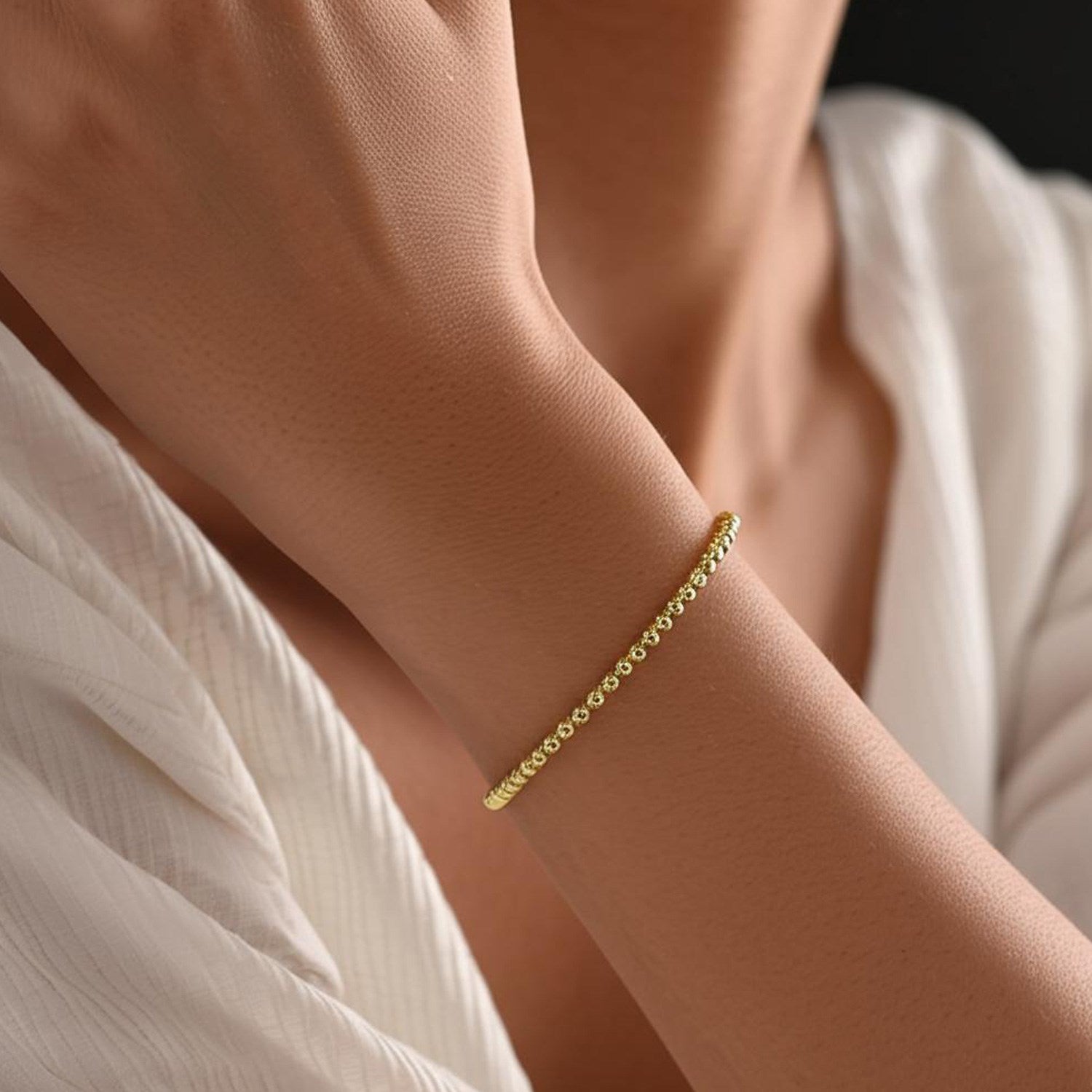 14k yellow gold high polish bead cuff bangle on a person's wrist.