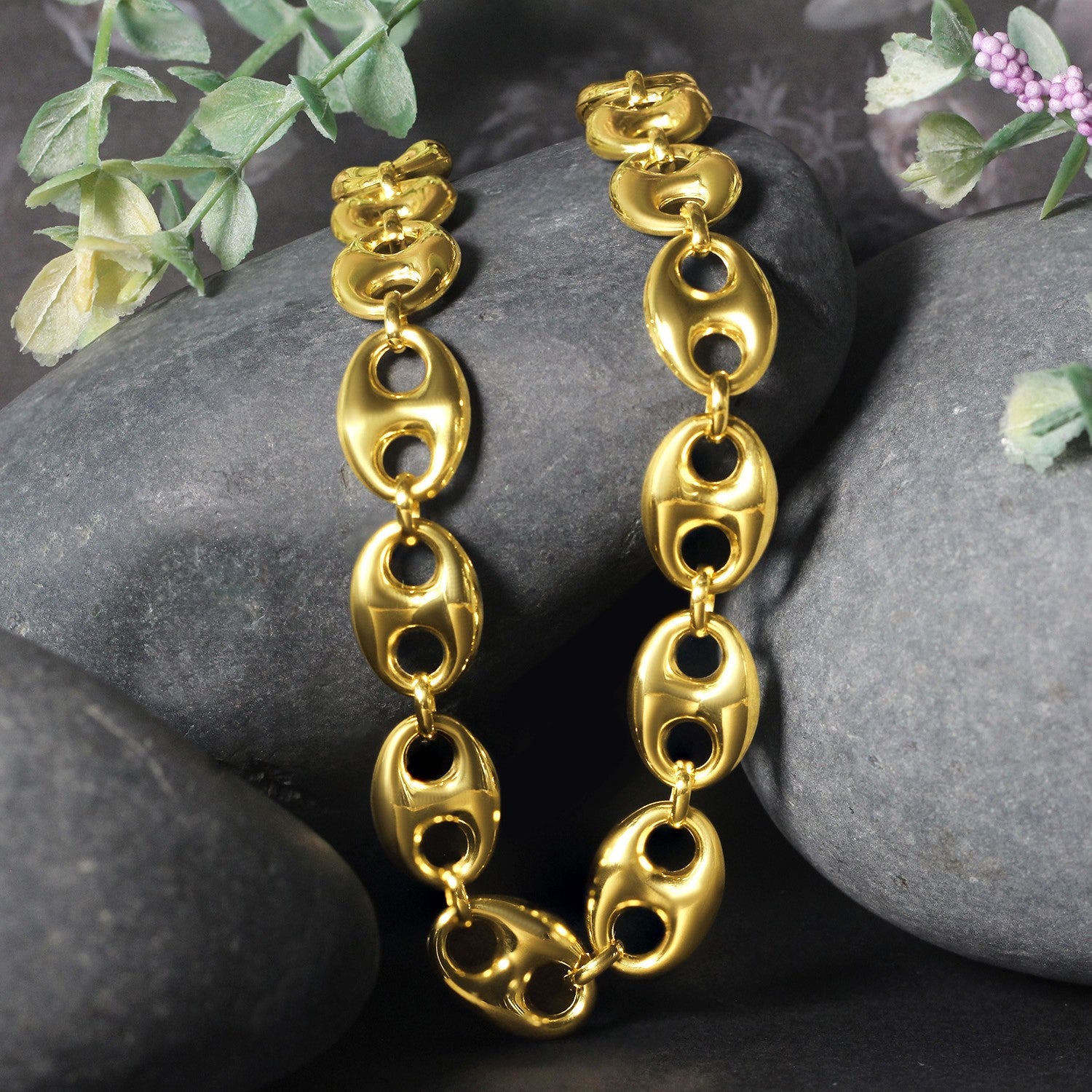 14k yellow gold puffed mariner link chain, 11.00 mm wide, displayed on dark rocks.