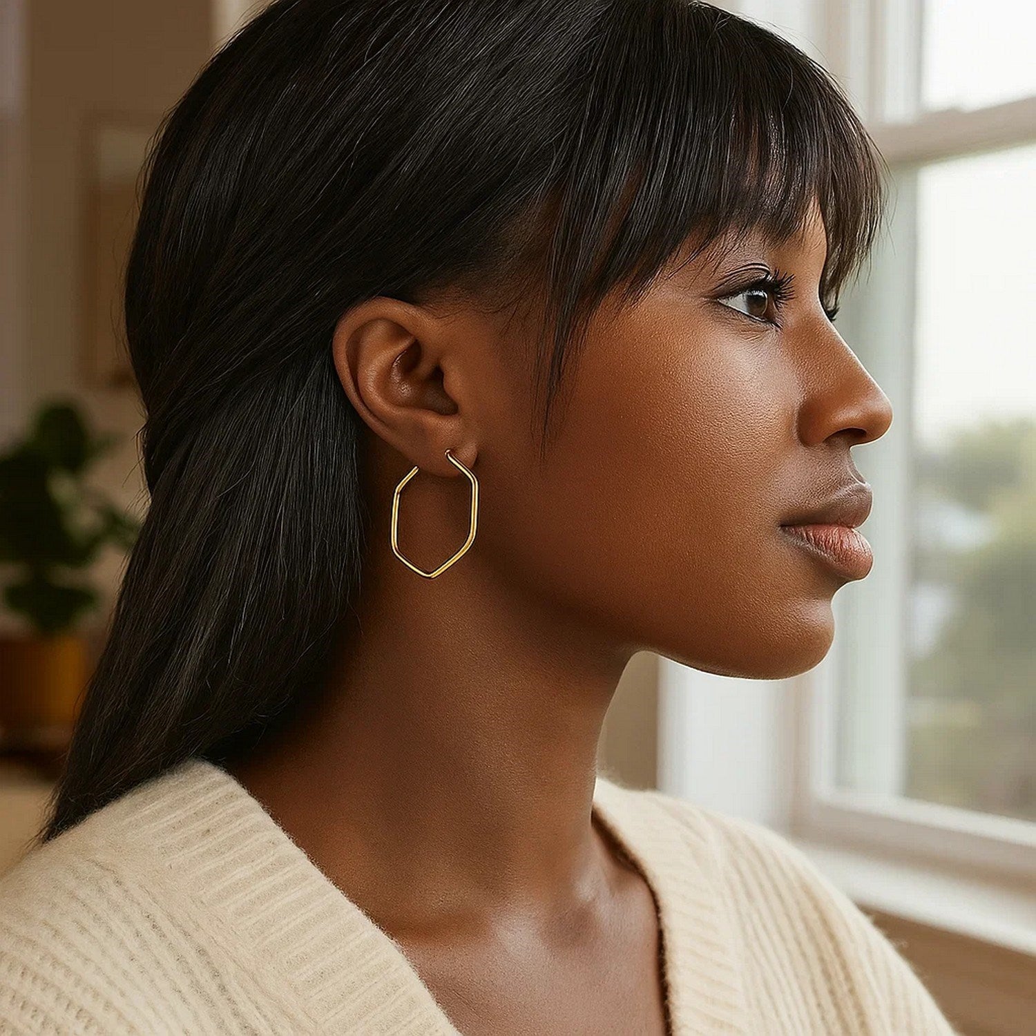 14K yellow gold hexagon hoop earrings with rounded edges on a woman.