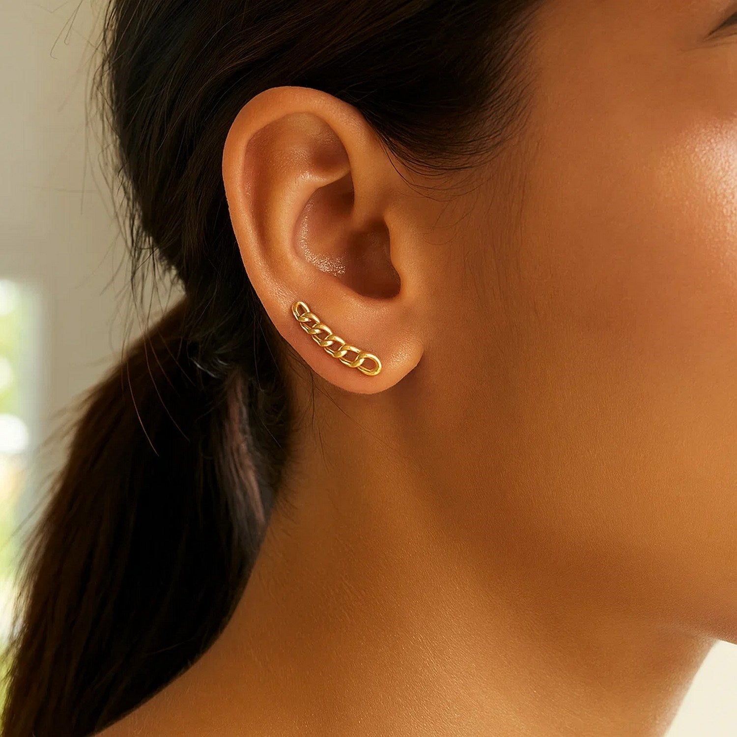 A 14k yellow gold ear climber earring with chain links is worn on an ear.