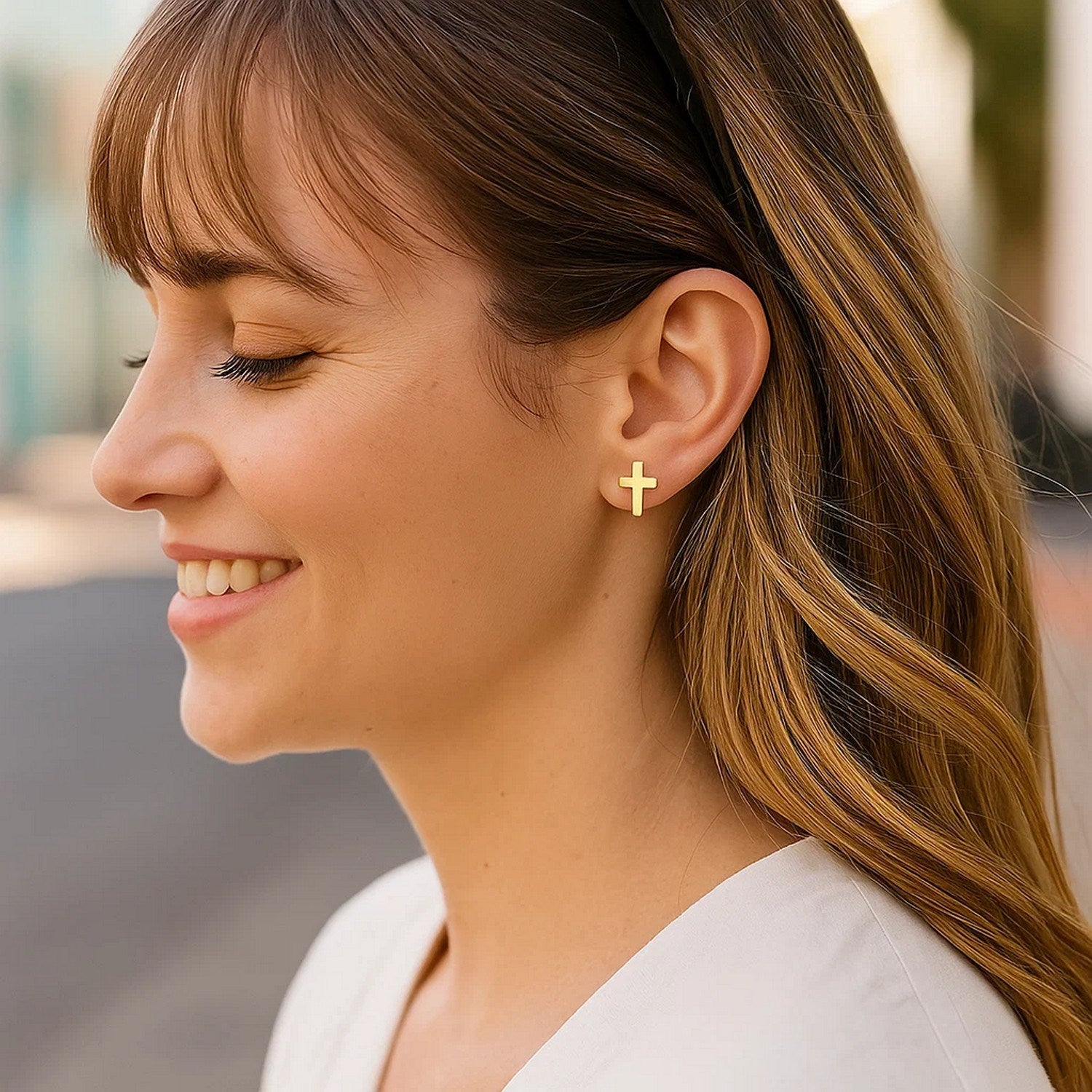 14k yellow gold cross post earrings on a woman's ear.