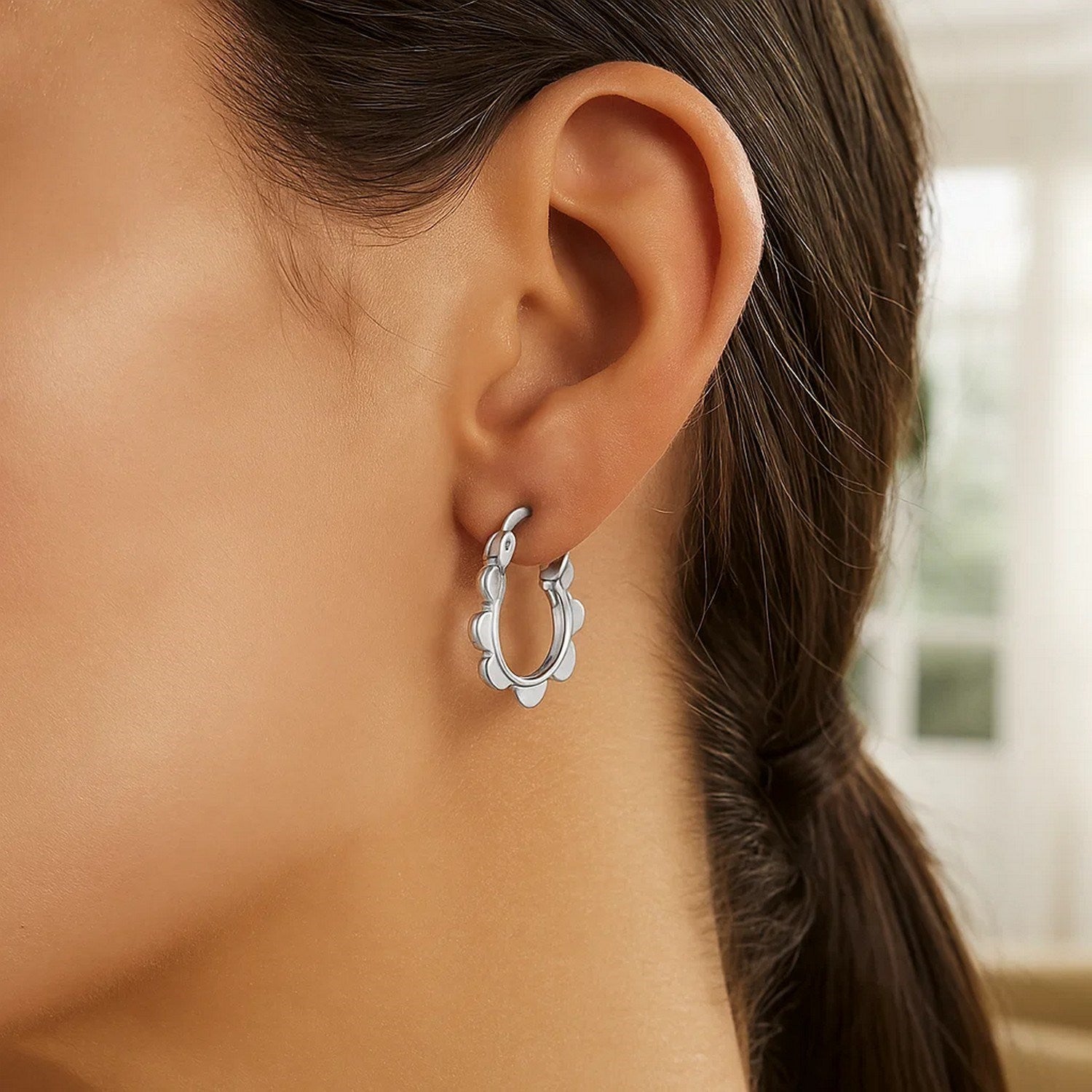 14k white gold scalloped hoop earring on a model's ear.