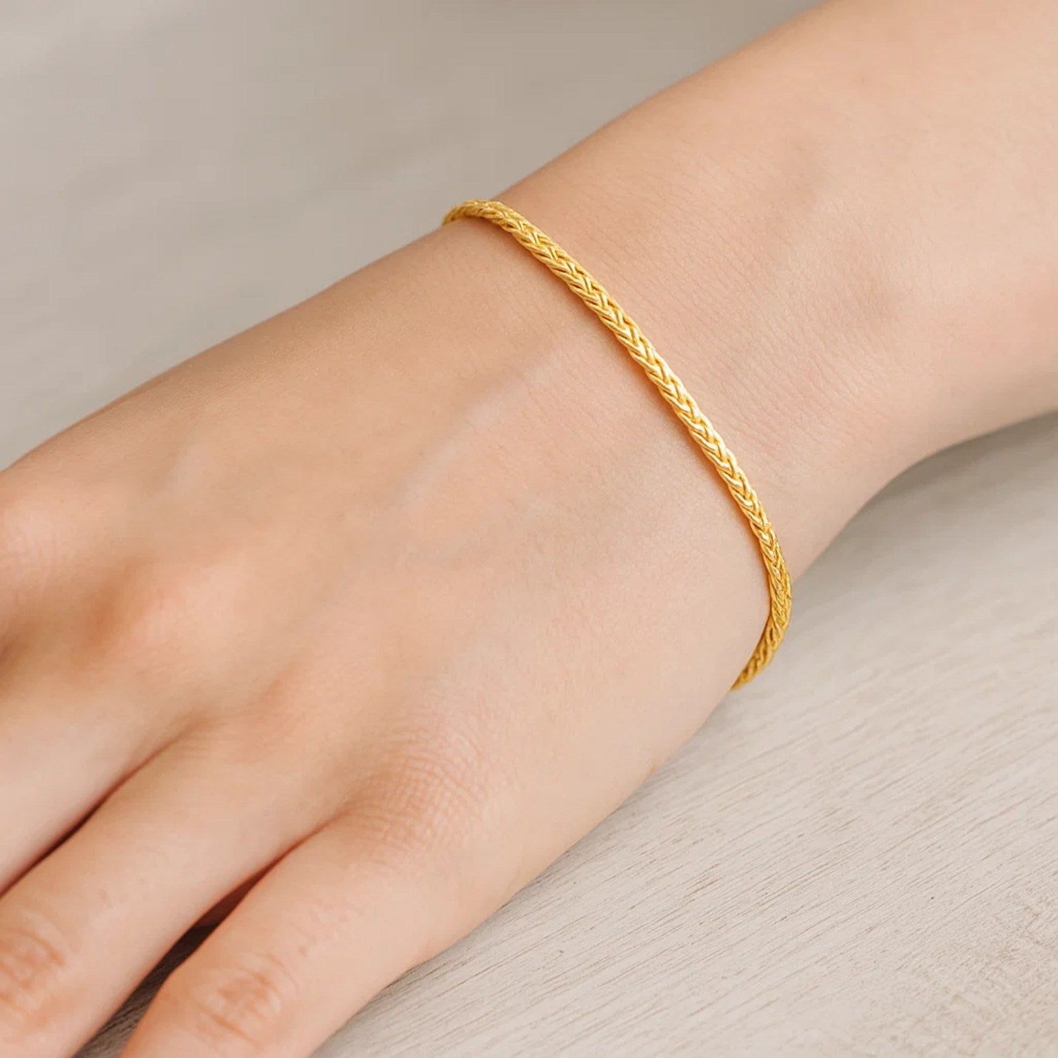 A 10k yellow gold wheat chain bracelet on a person's wrist.