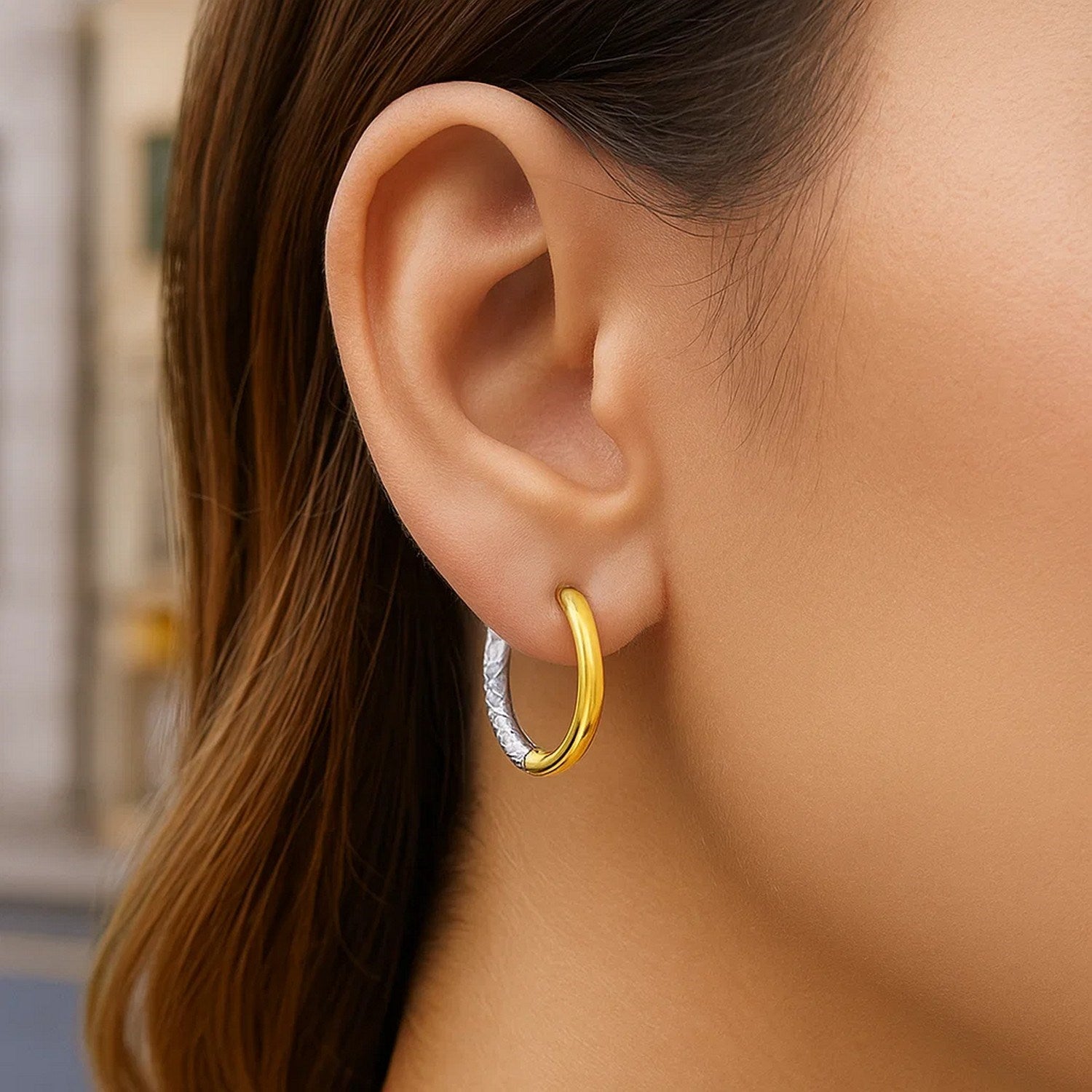 Two-tone 14k gold hoop earrings with a textured white gold and smooth yellow gold design.