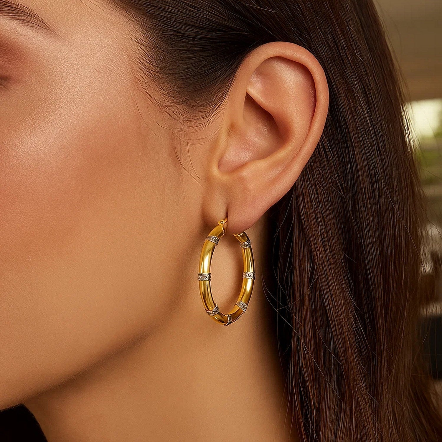 14k two-tone gold alternate textured hoop earrings on a model's ear.