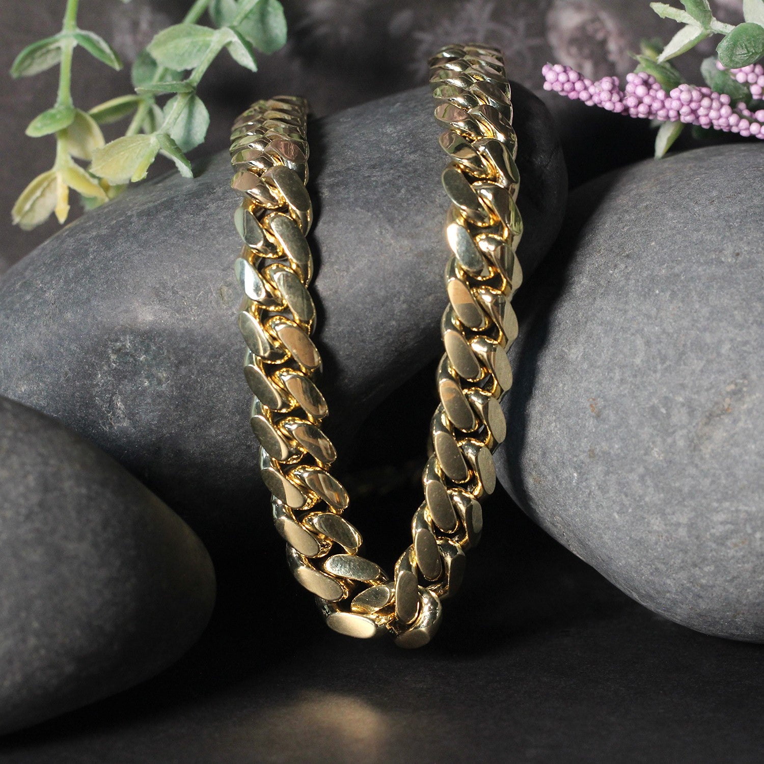 14k yellow gold classic Miami Cuban solid chain, 10.10 mm wide, displayed on dark rocks.
