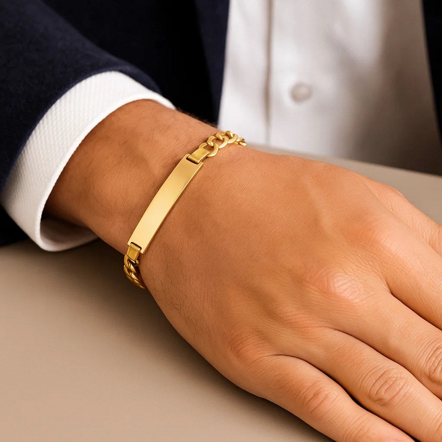 A man wears a polished 14k yellow gold narrow curb chain ID bracelet.