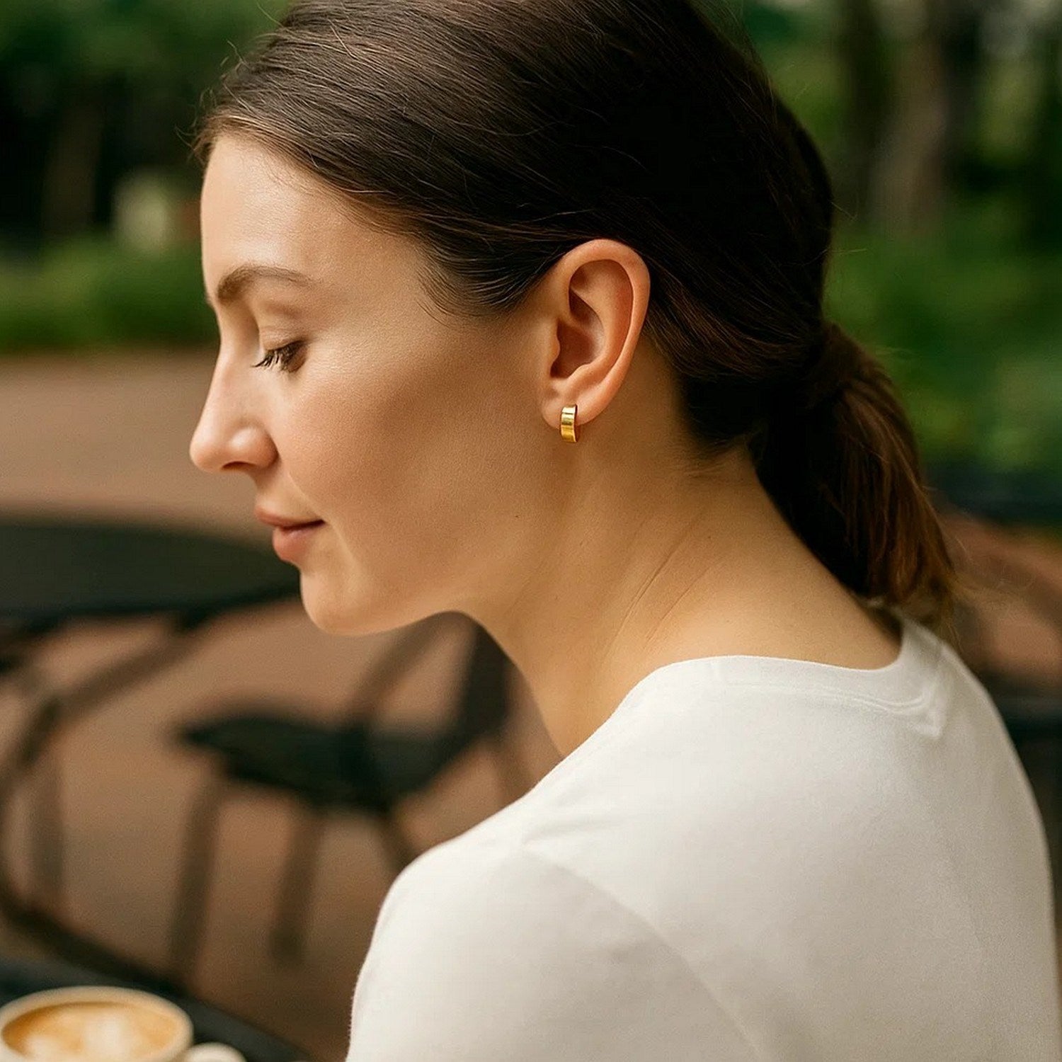 10k yellow gold snuggable hoop earrings on a woman's ear.