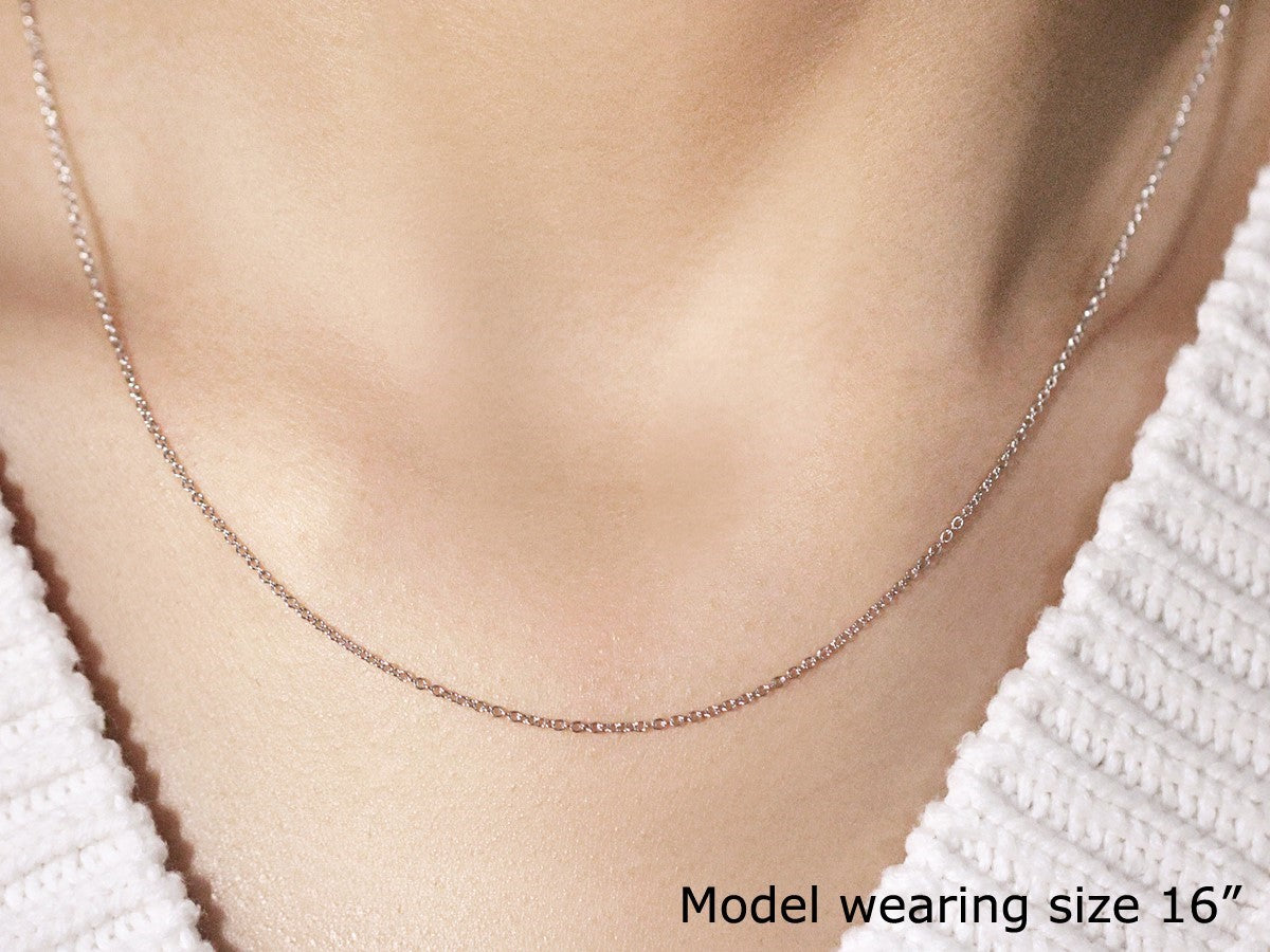 A 14k white gold round cable link chain, 1.10 mm wide, worn by a model.