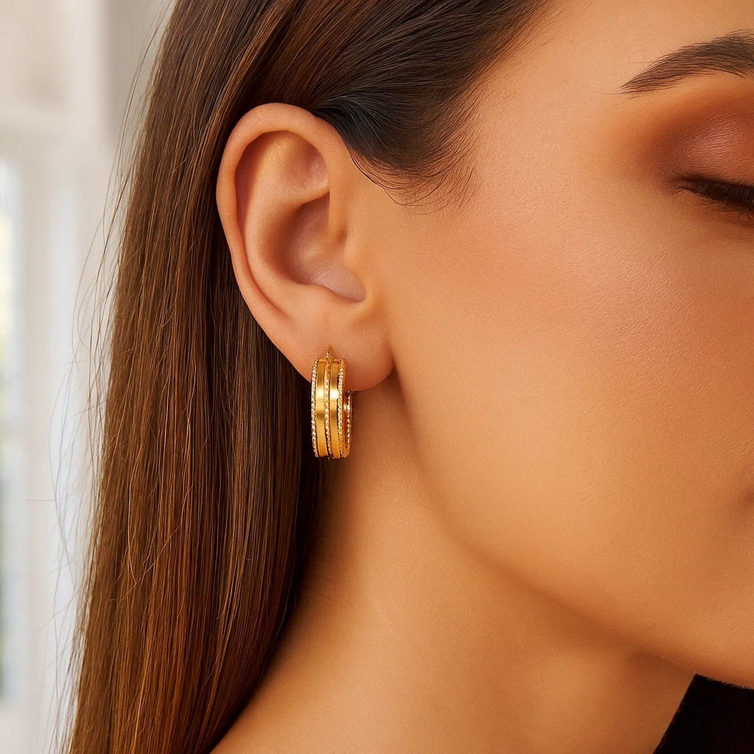 14K yellow gold double sparkle spring hoop earrings on a woman's ear.