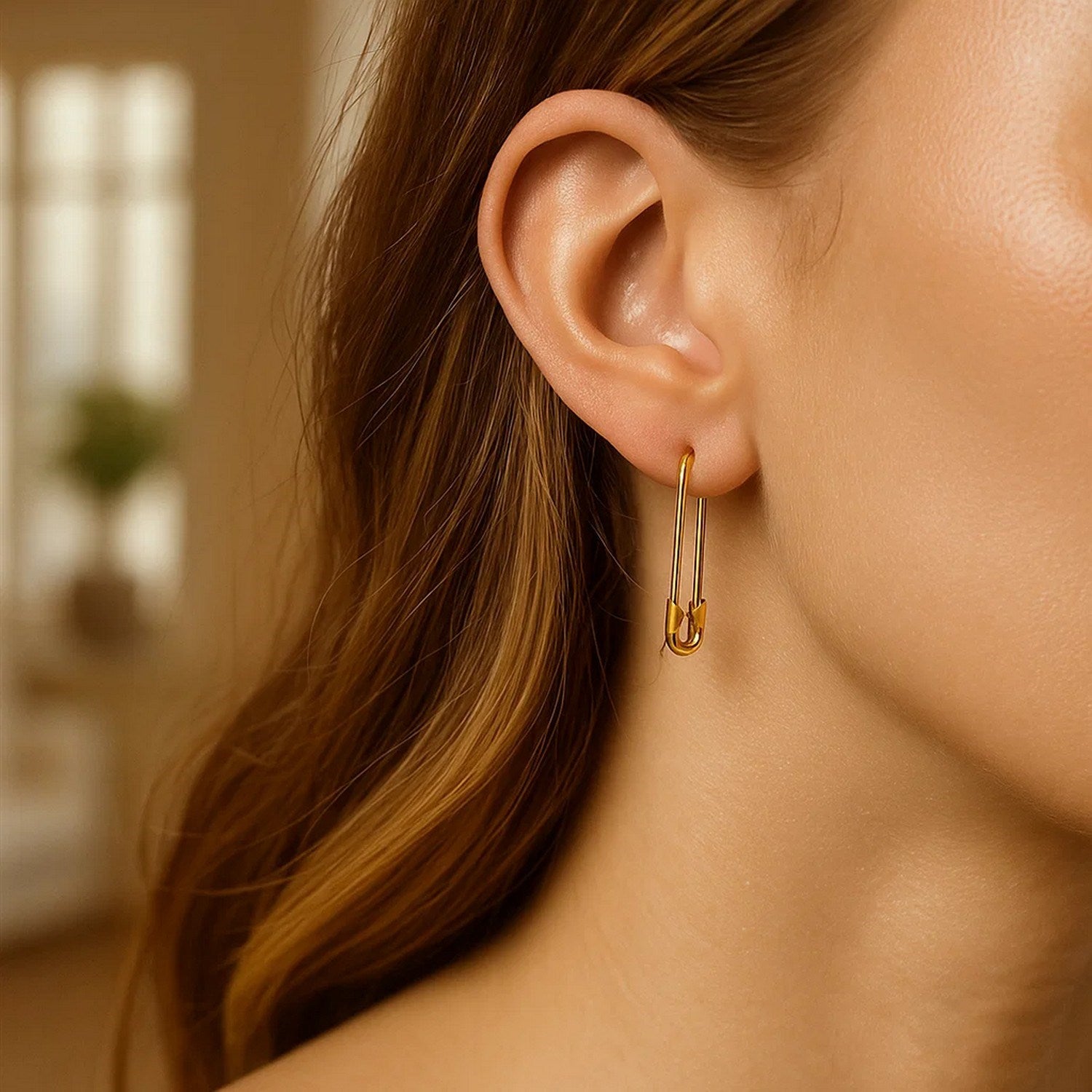 A woman wears a 14k yellow gold safety pin earring.