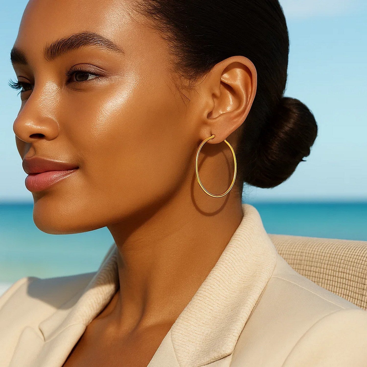 10k yellow gold polished hoop earrings on a woman with a beach background.