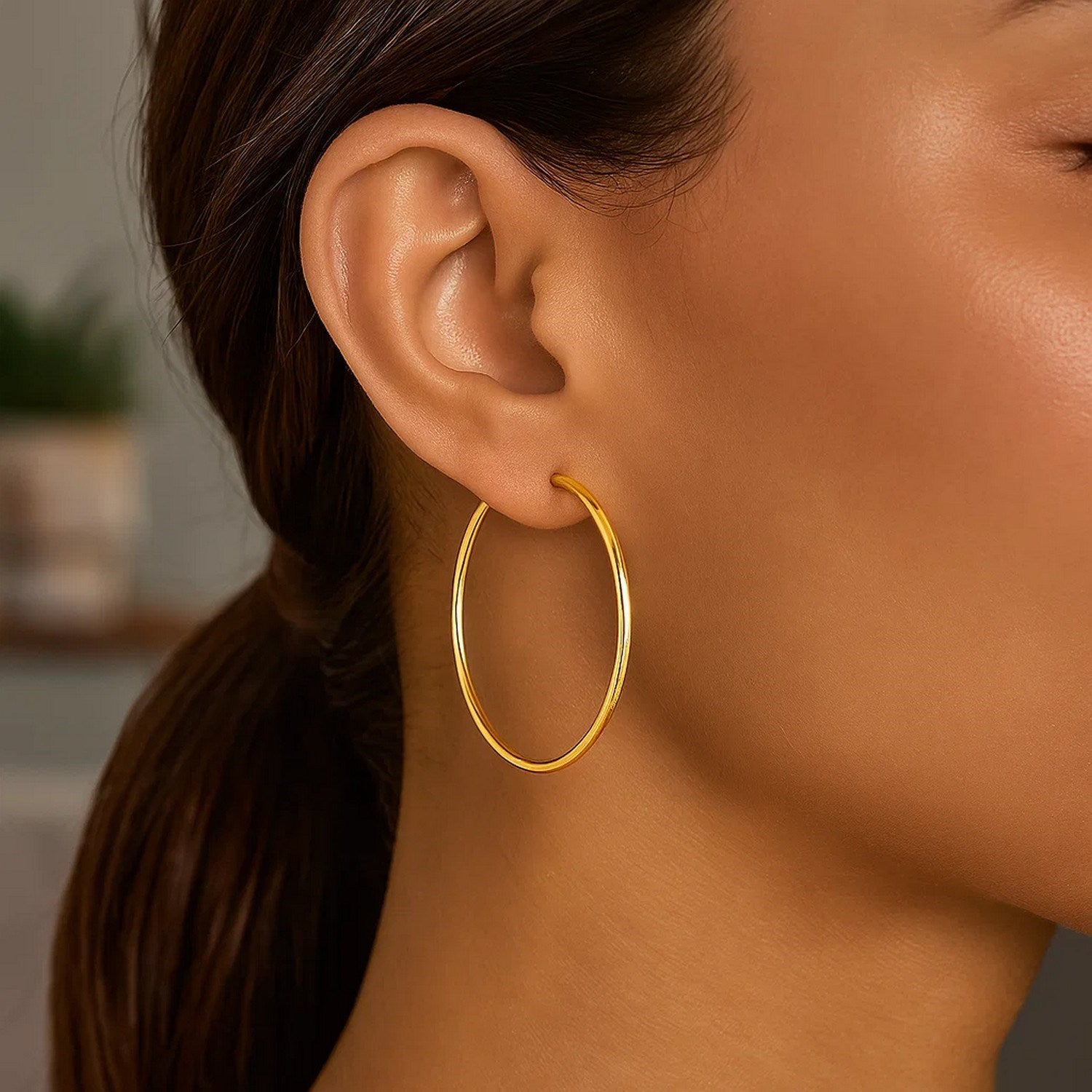 10k yellow gold polished hoop earrings are worn on a person's ear.
