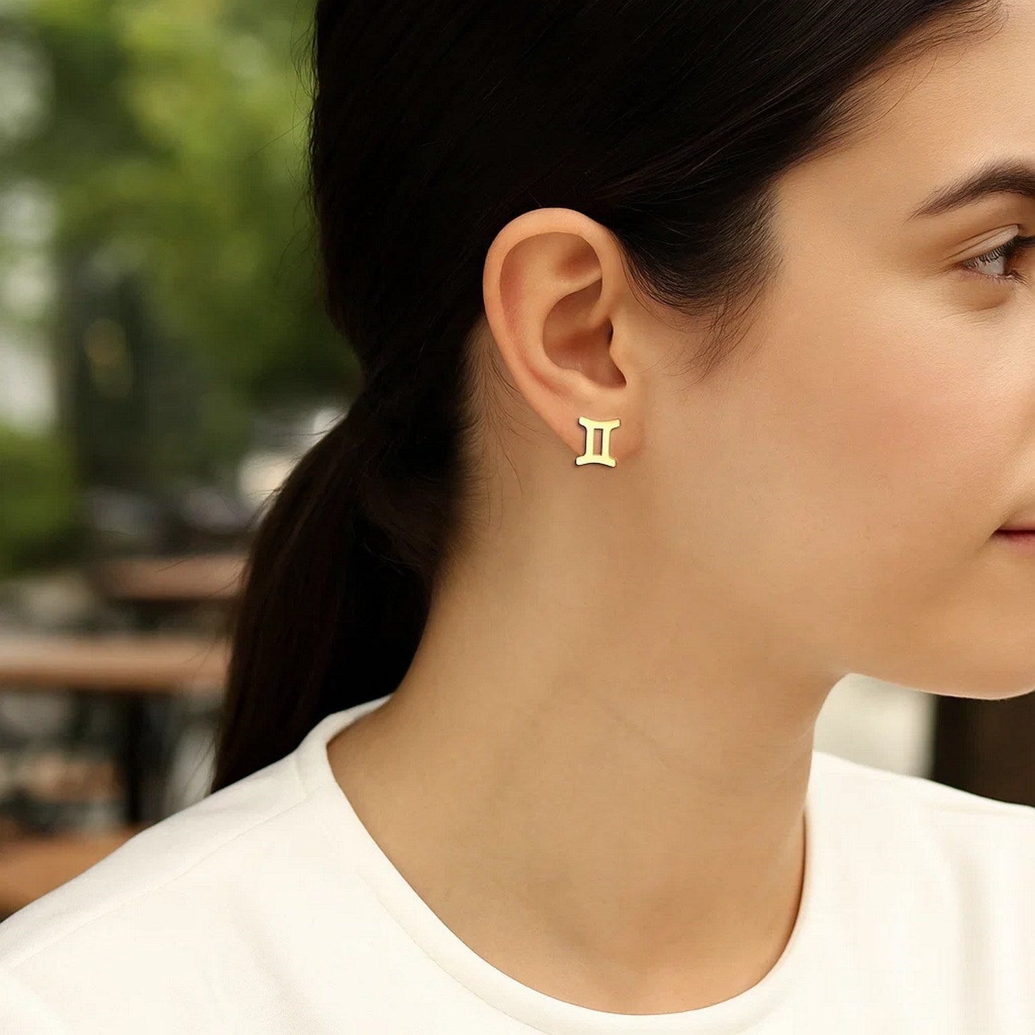 14K yellow gold Gemini stud earrings on a woman's ear.