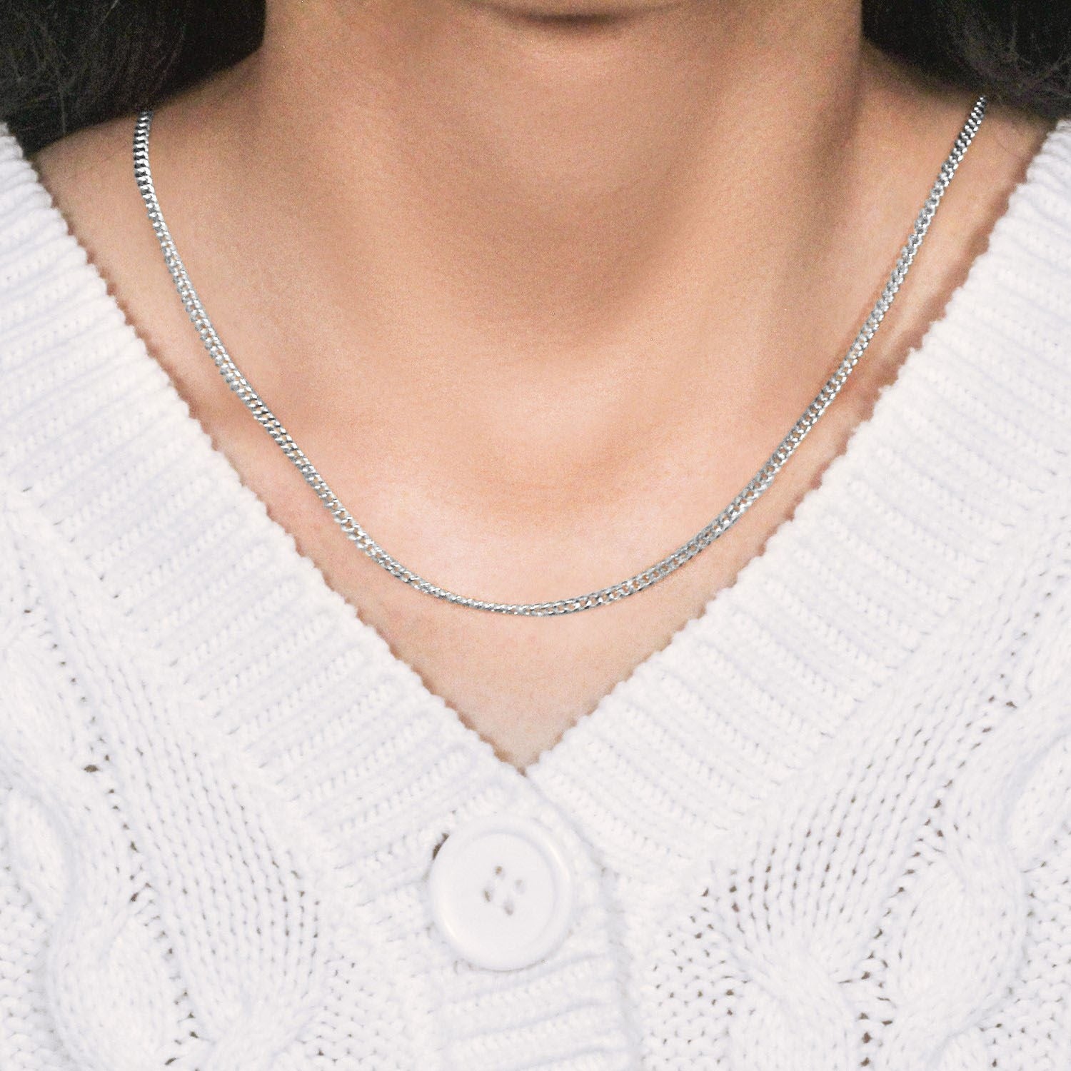 A 14K white gold gourmette chain is worn around a person's neck.