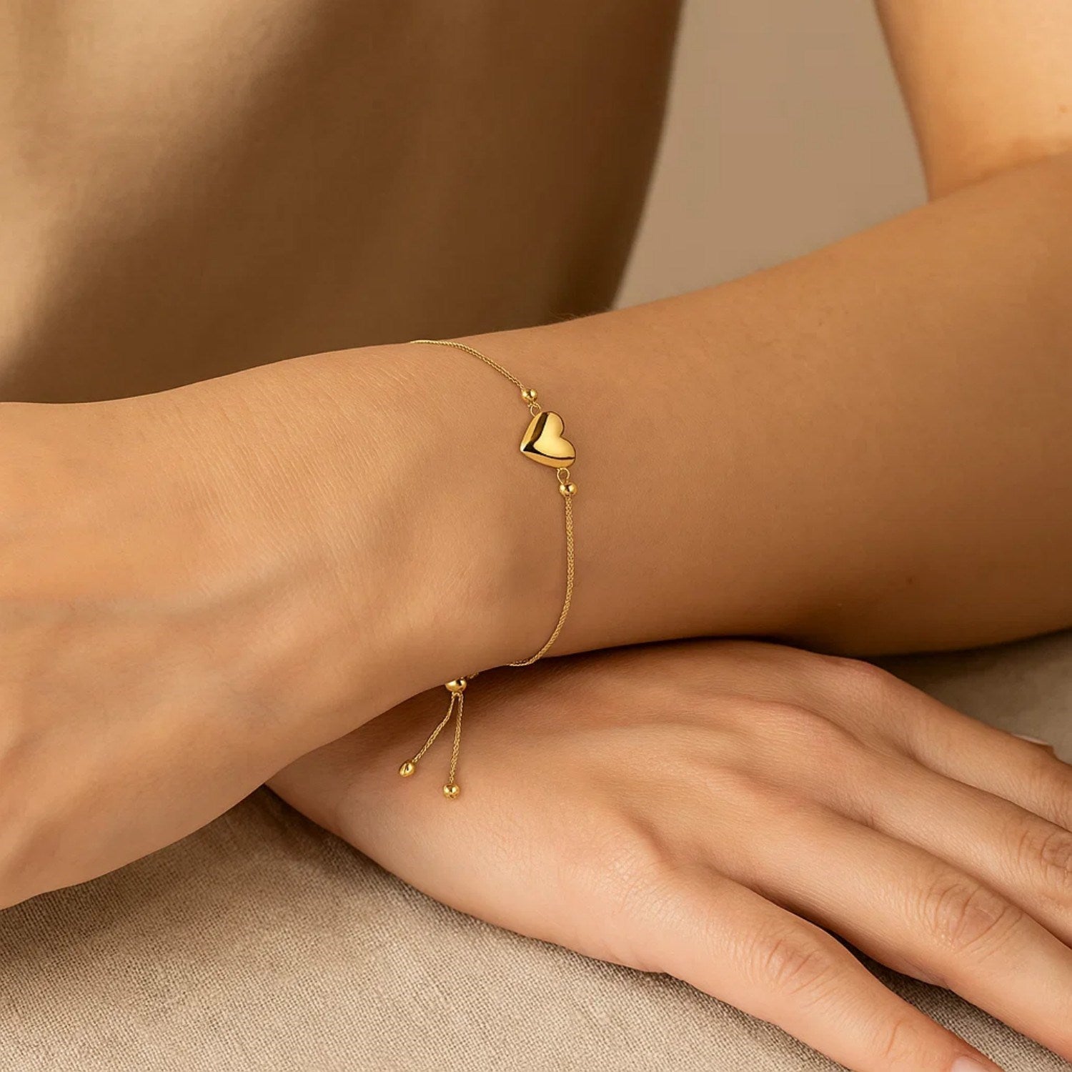 Adjustable 14K yellow gold bracelet with a puffed heart charm and drawstring clasp.