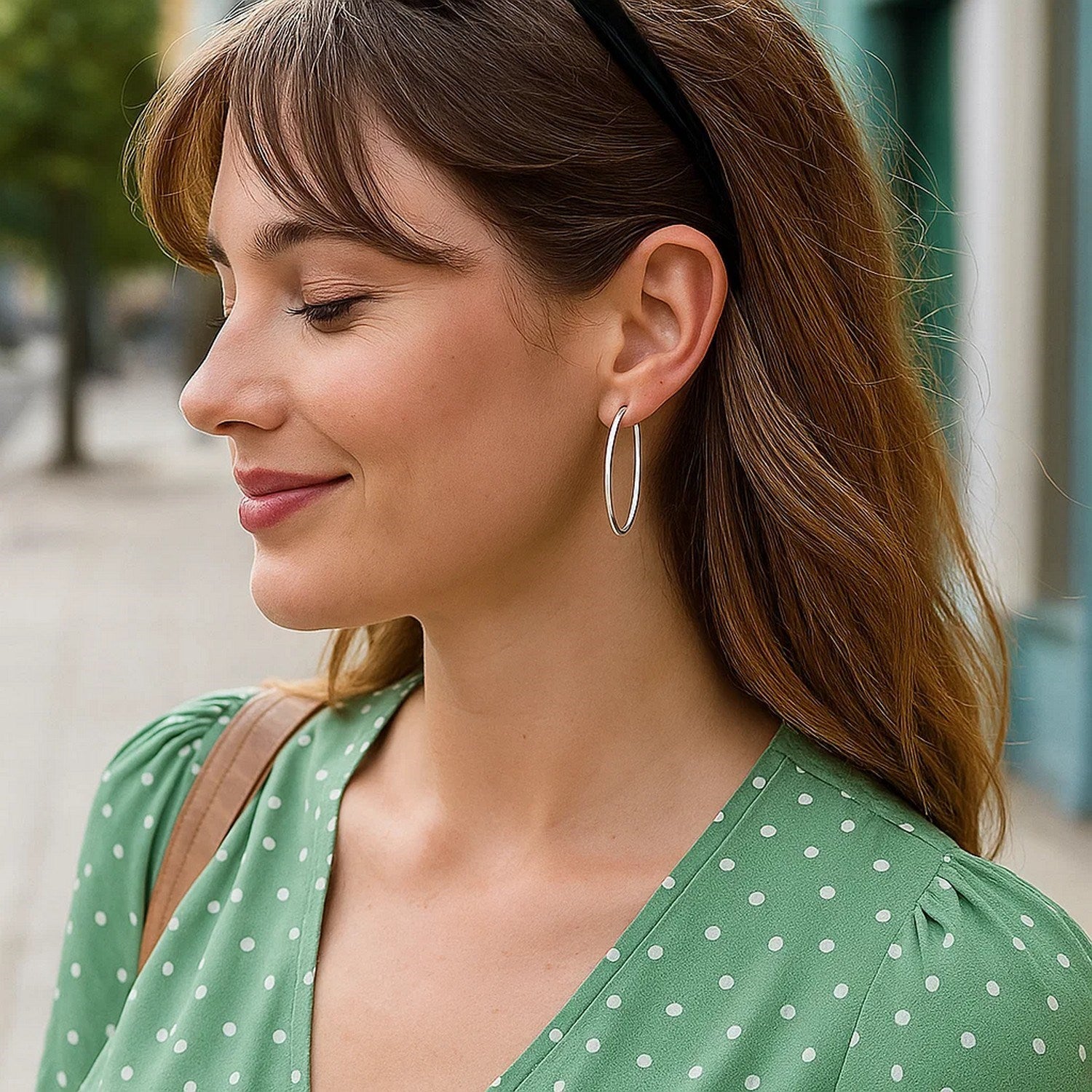14k white gold slim oval hoop earrings on a woman in a green polka dot dress.