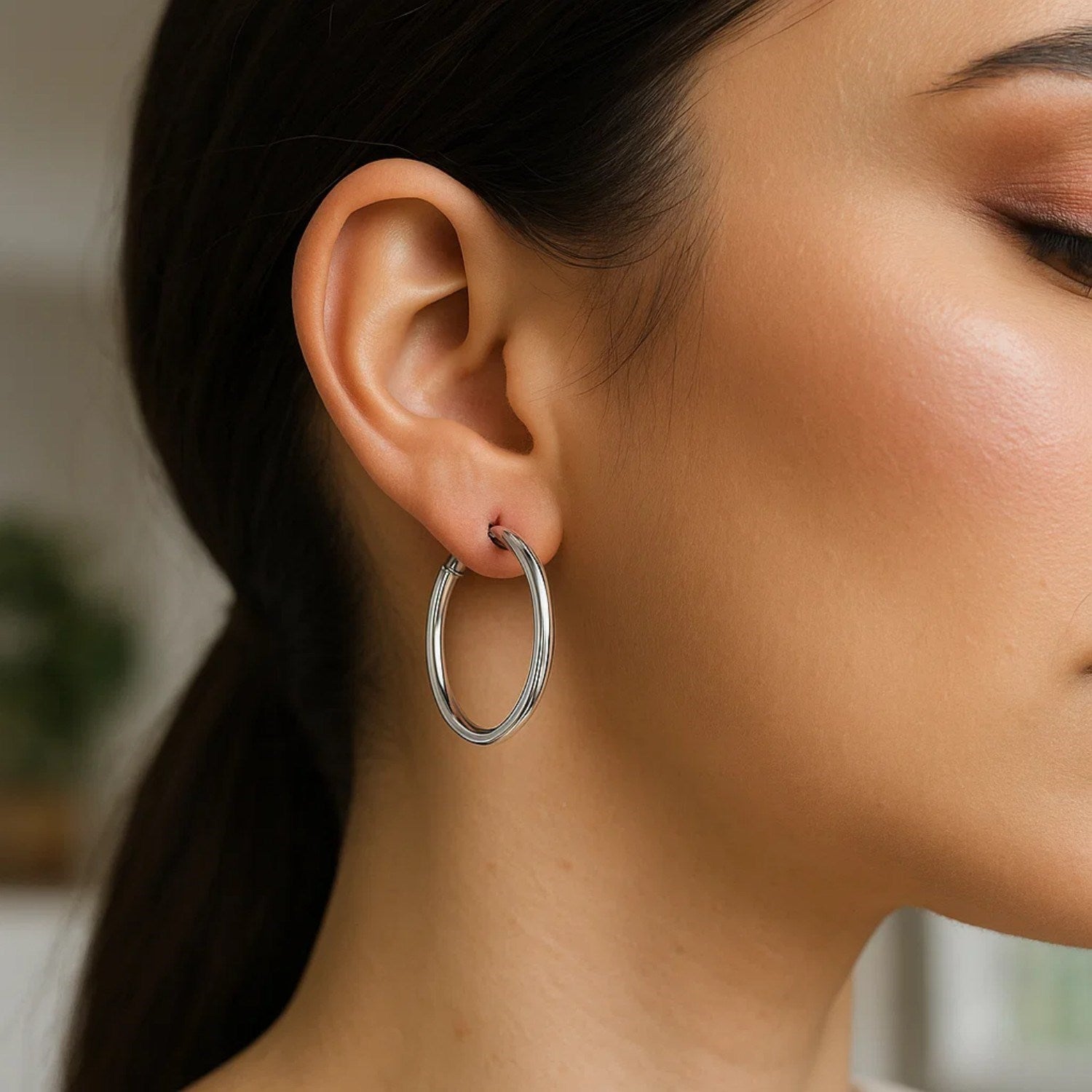 Sterling silver hoop earrings with polished rhodium plating on a woman's ear.