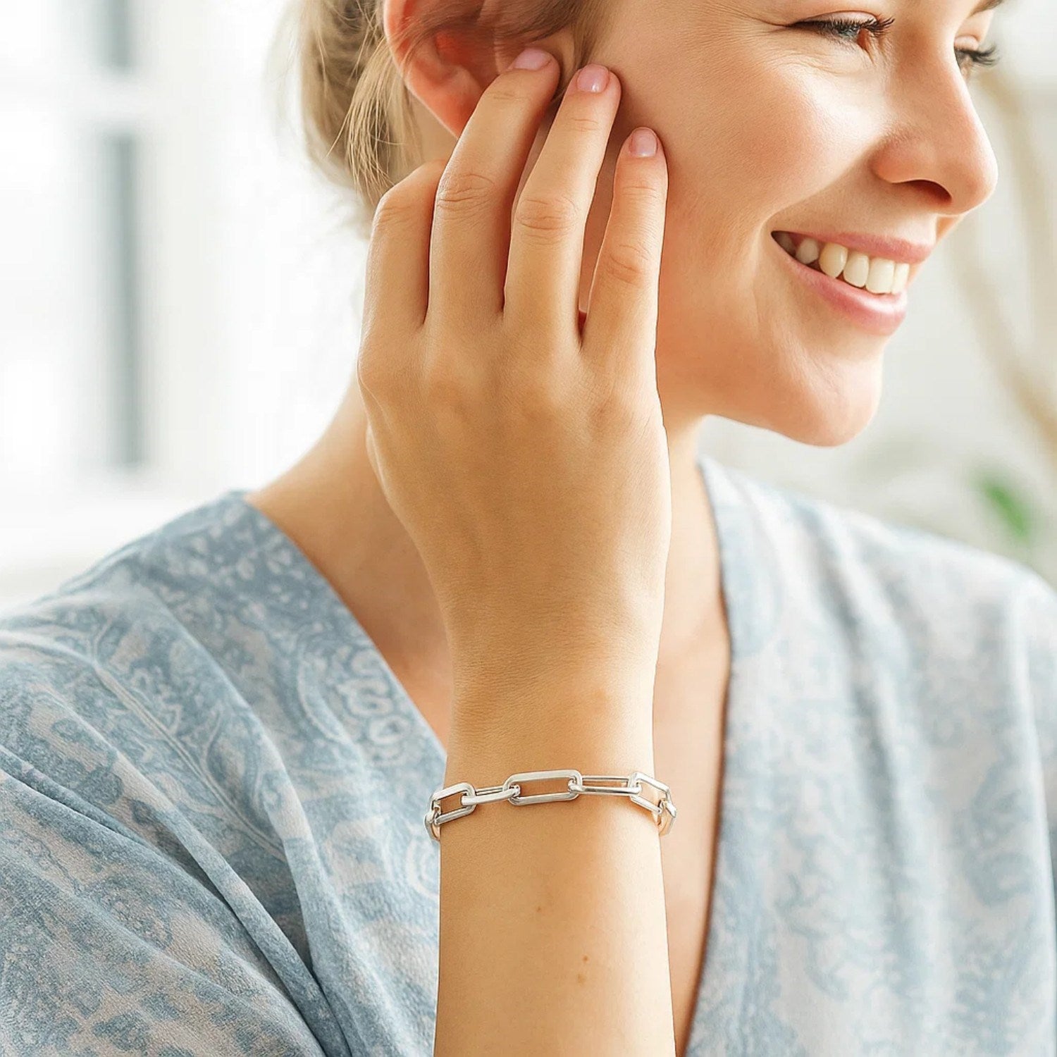 14K white gold extra wide paperclip chain bracelet on a woman's wrist.