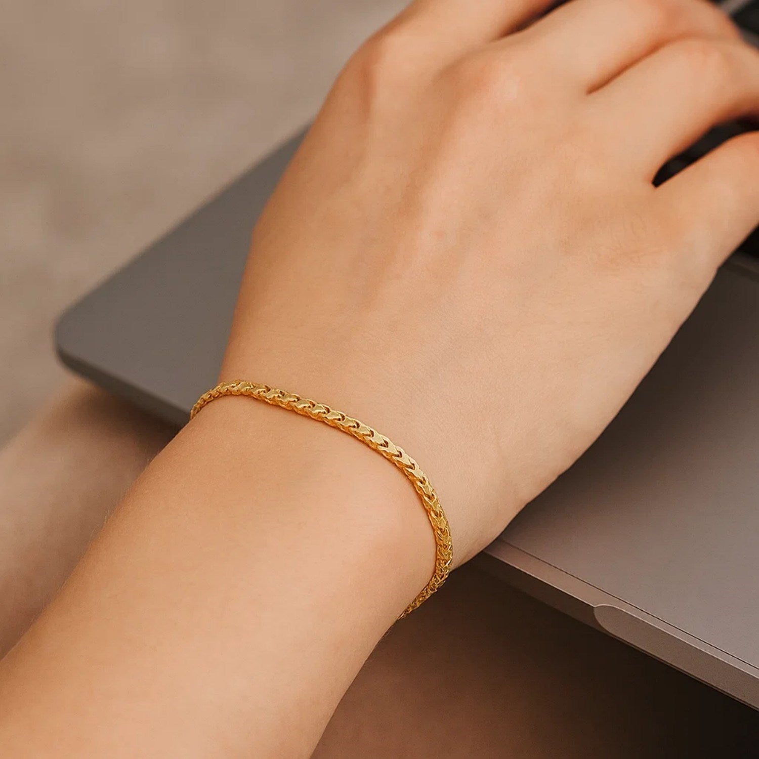 A 14k yellow gold solid diamond cut round franco bracelet on a person's wrist.