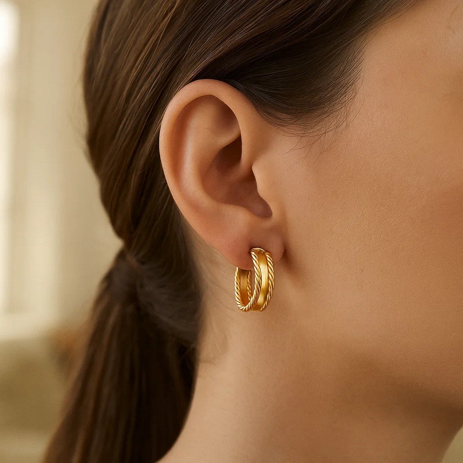 14K yellow gold triple row hoop earrings on a woman's ear.