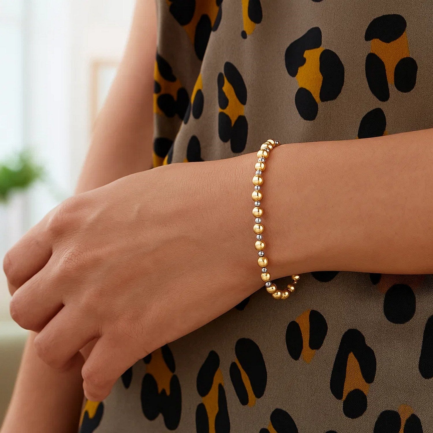 14k two-tone gold polished diamond cut bead bracelet on a person's wrist.
