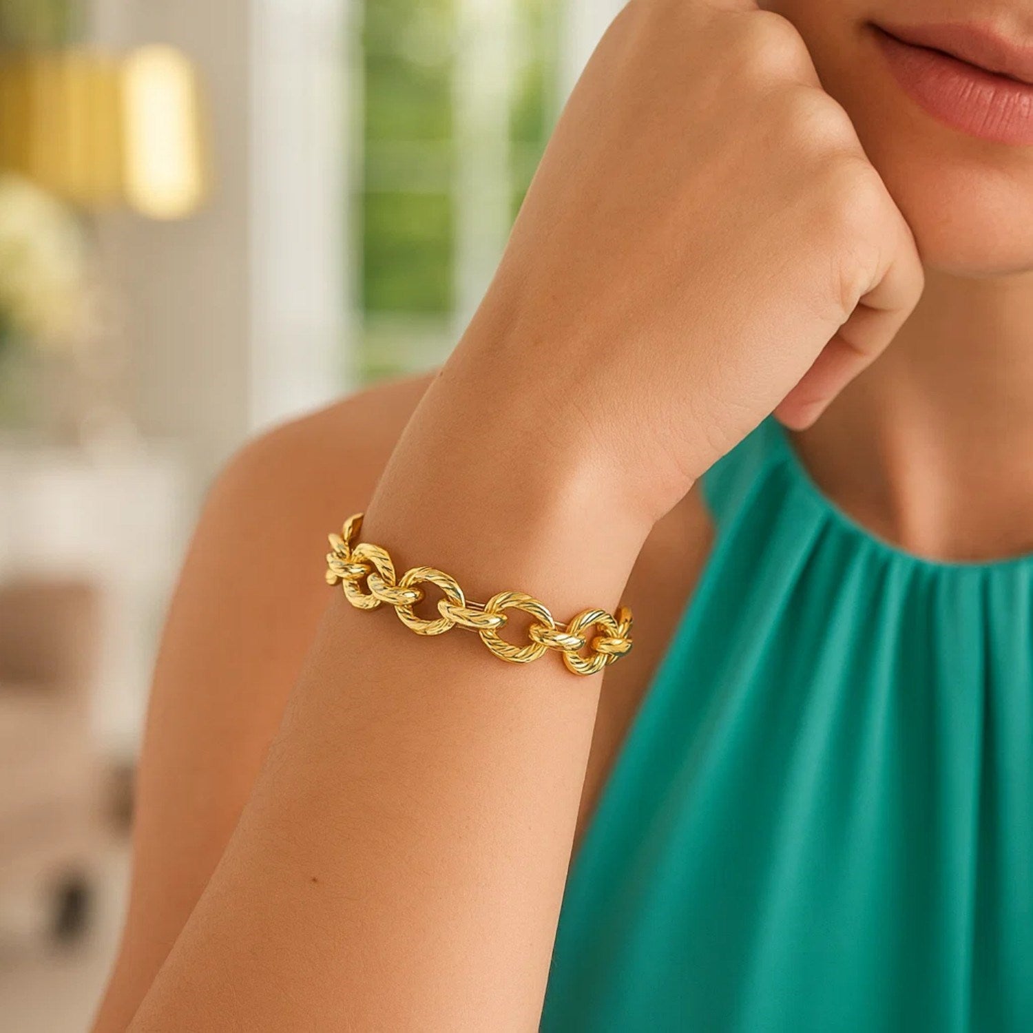 Textured oval link bracelet in 14k yellow gold on a woman's arm.