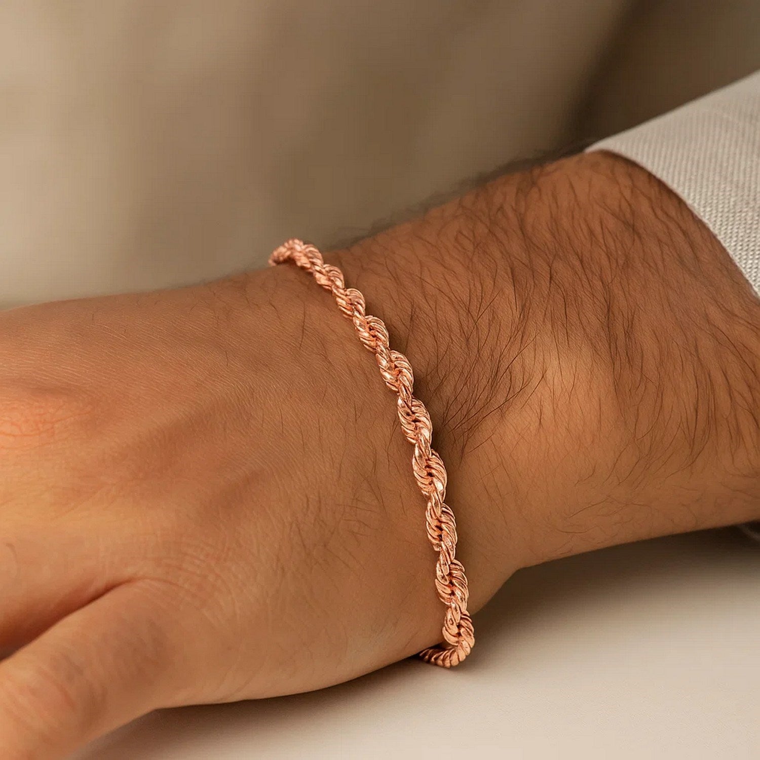 A 14k rose gold solid diamond cut rope bracelet on a person's wrist.