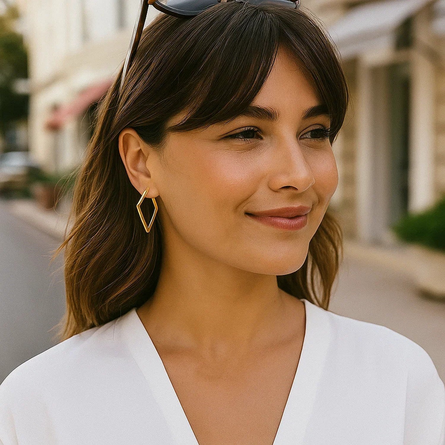 14K yellow gold diamond motif hoop earrings are worn by a woman in a white top.