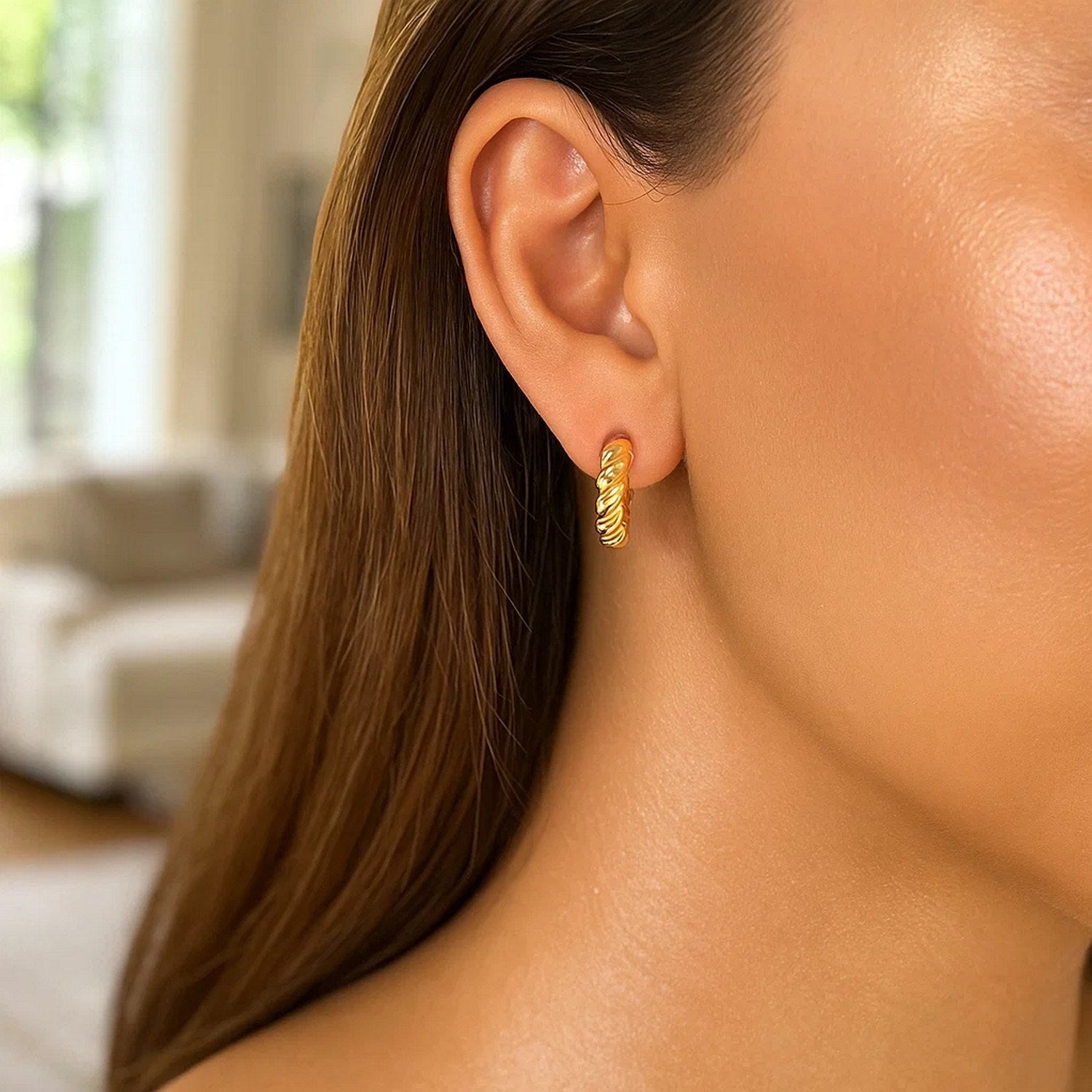 A single 14k yellow gold polished twisted hoop earring is worn on an ear.