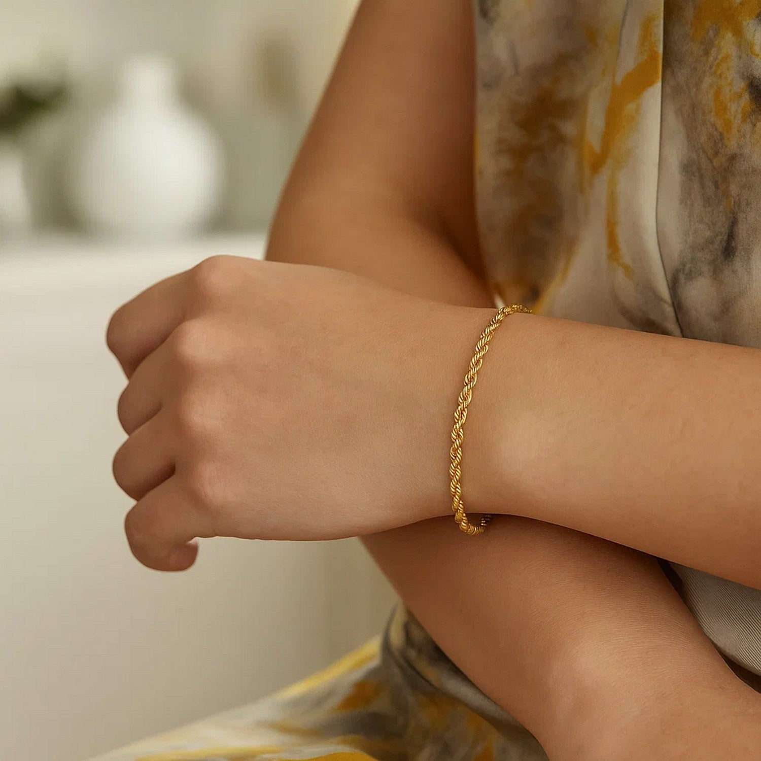 A 14k yellow gold silk rope chain bracelet on a person's wrist.