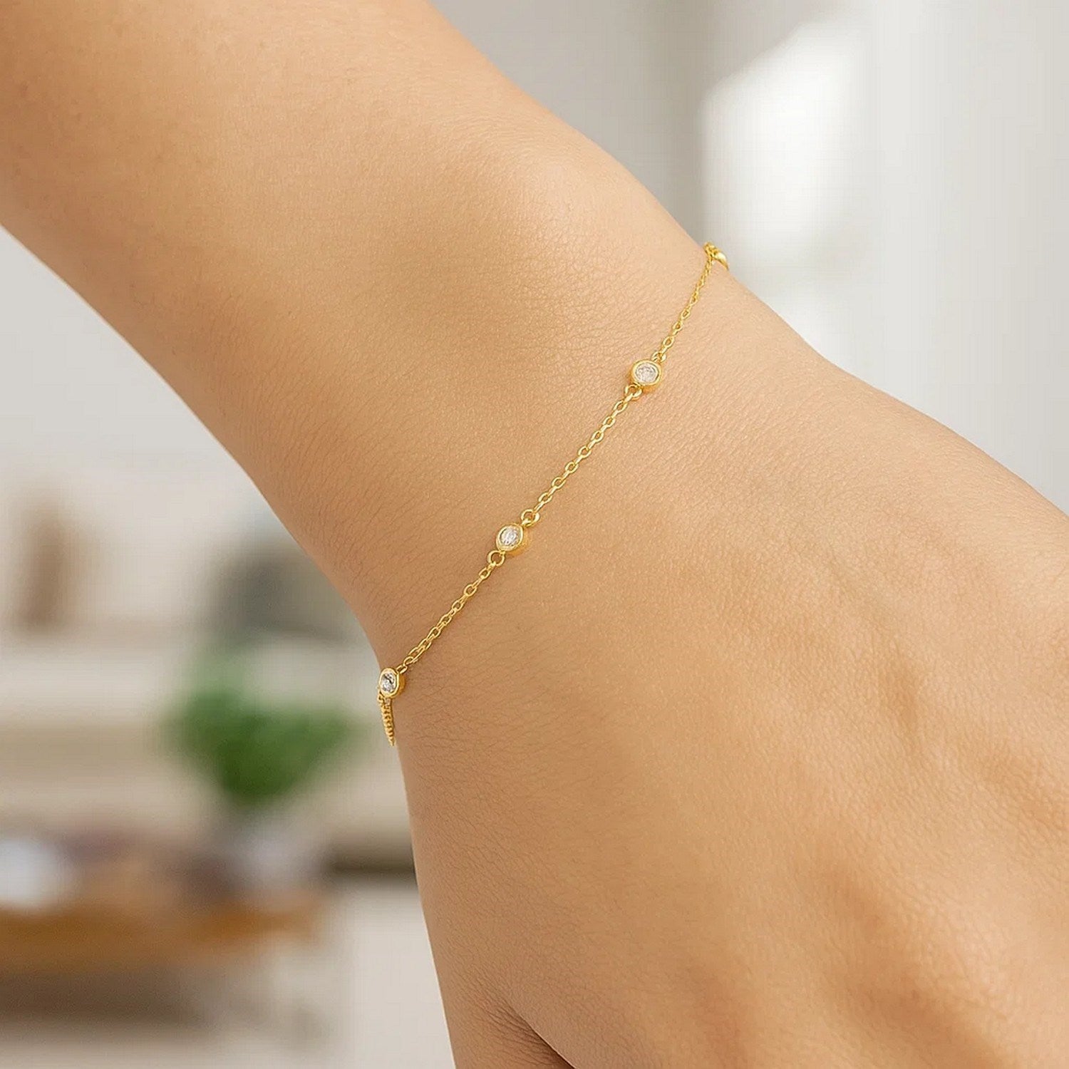 14k yellow gold bracelet with six round diamond stations on a woman's wrist.