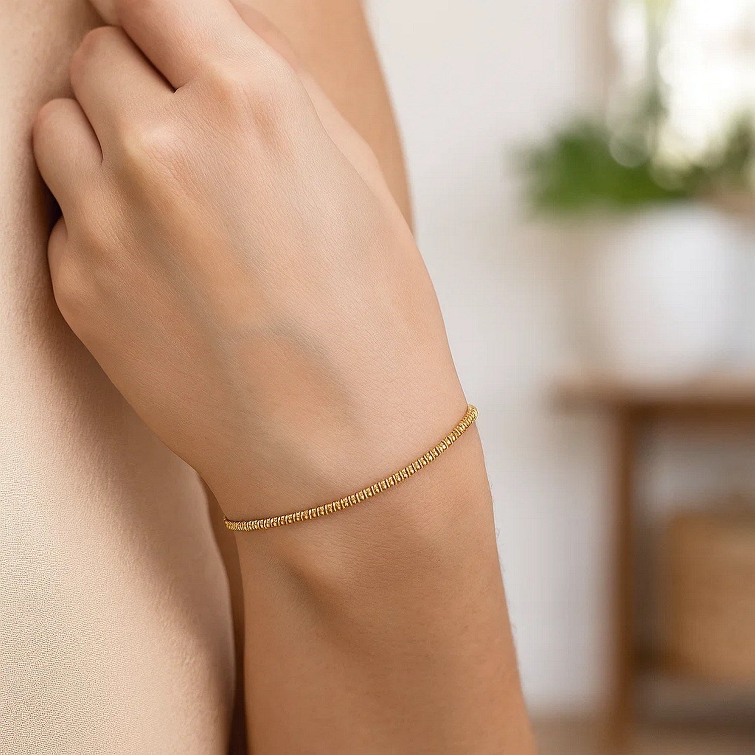 14K yellow gold sparkle spring chain bracelet on a person's arm.