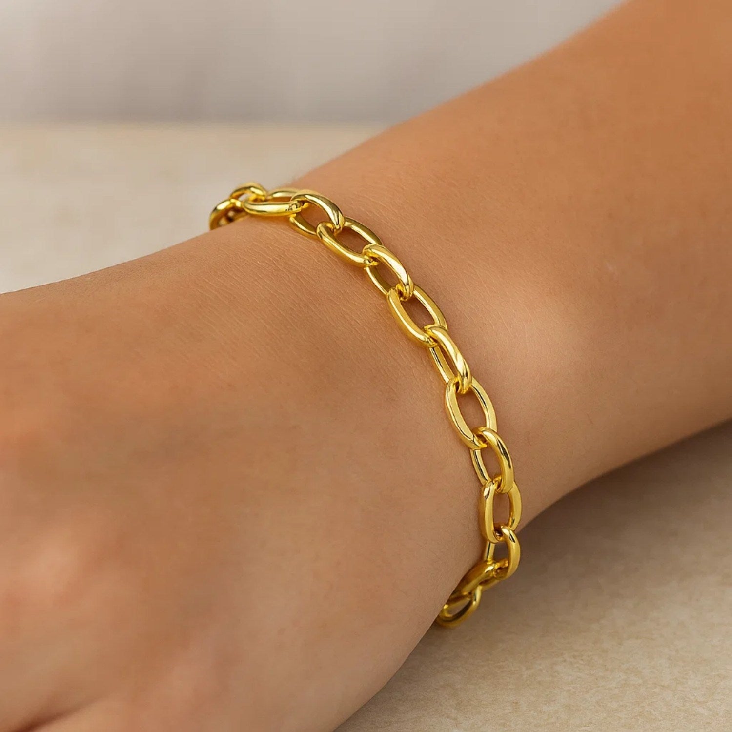 A 14k yellow gold cable chain style bracelet with polished oval links on a wrist.