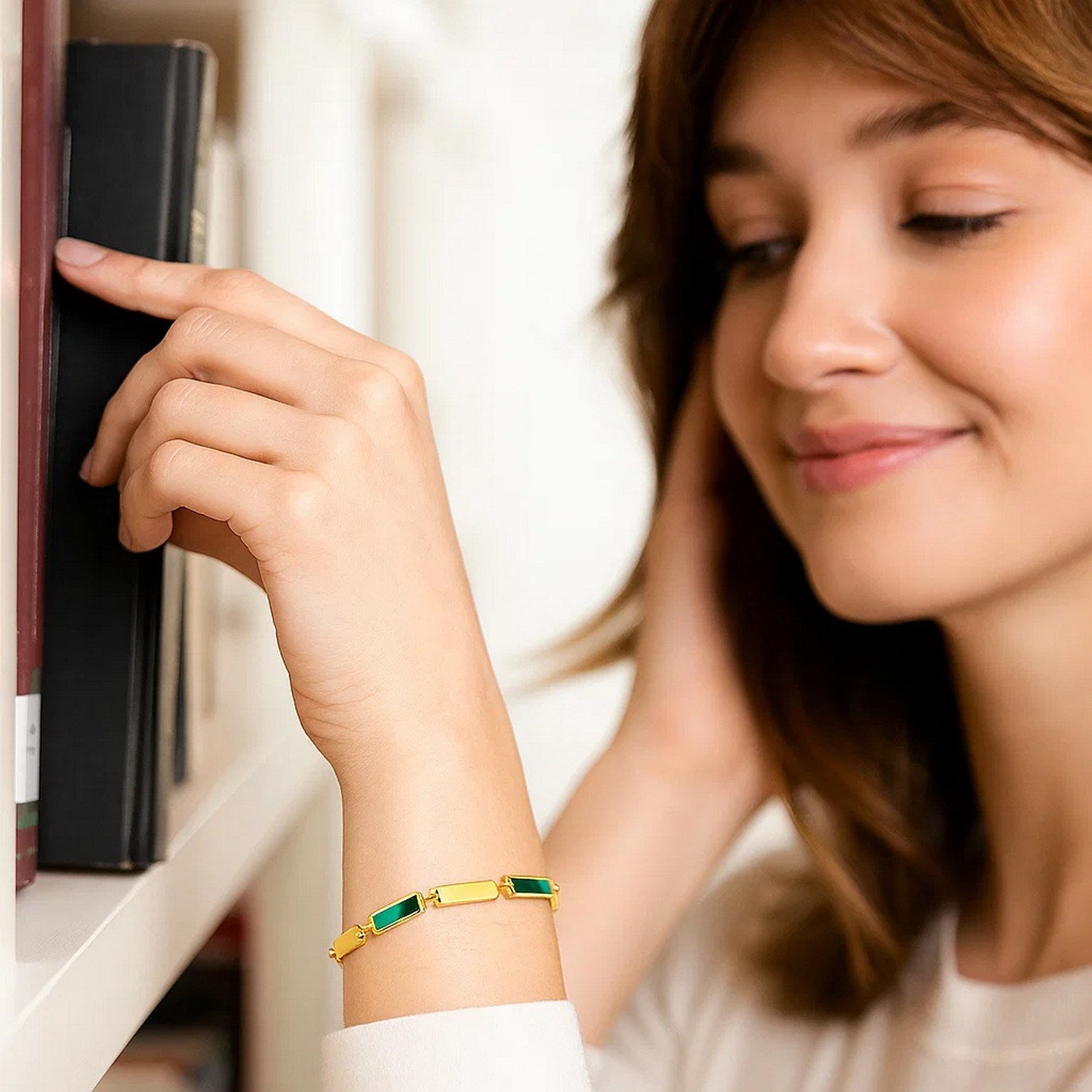 14K yellow gold bracelet with rectangular malachite links on a woman's wrist.