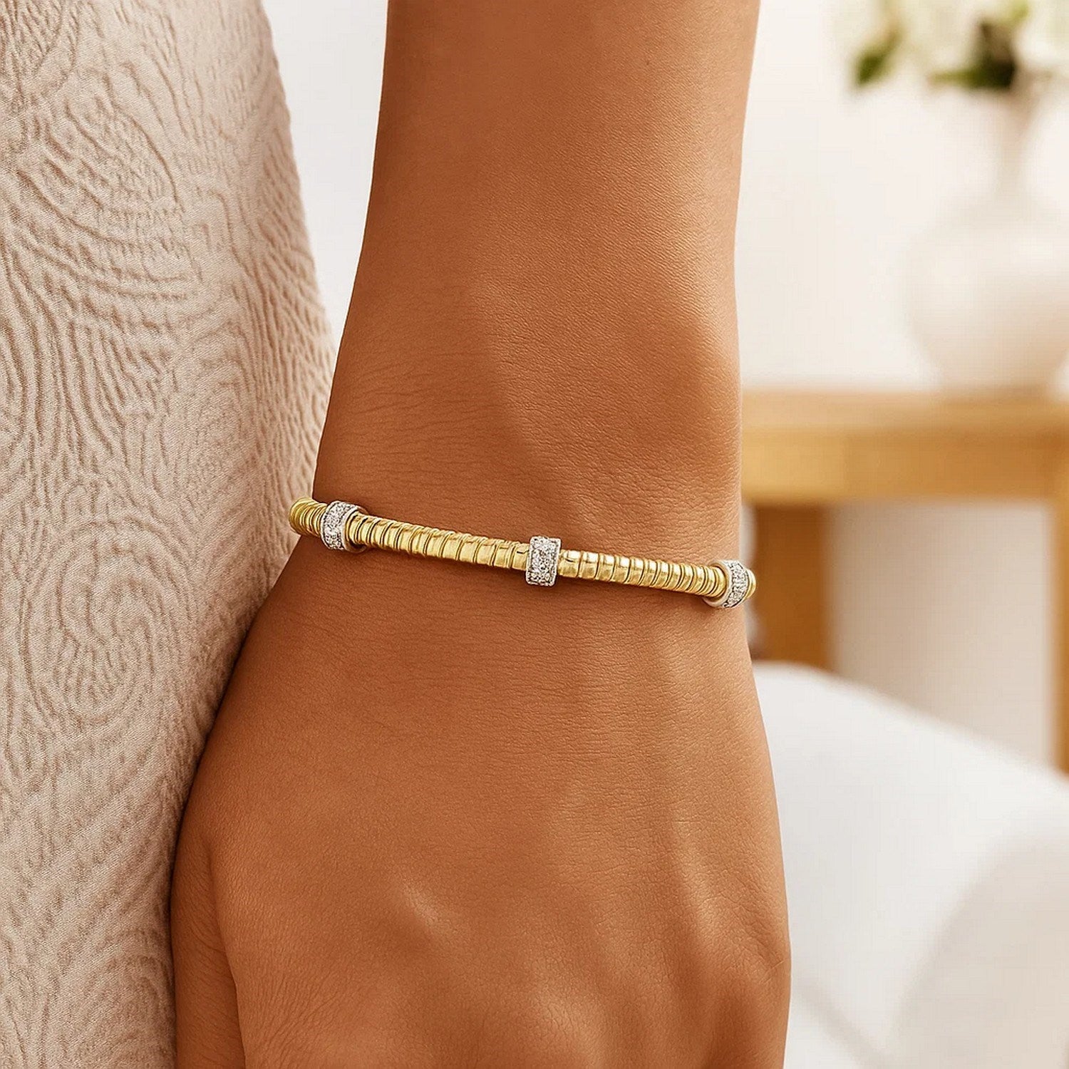 14K yellow gold Tubogas cuff bracelet with three diamond stations on a person's wrist.