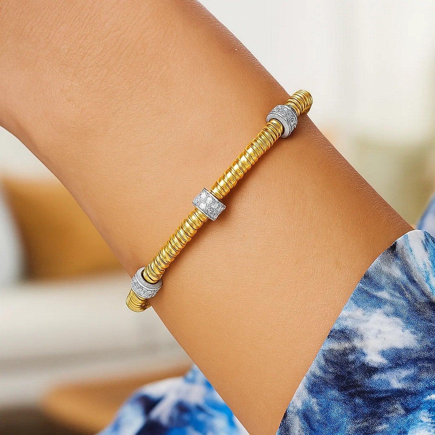 14K yellow gold tubogas cuff bracelet with three diamond stations on a person's arm.