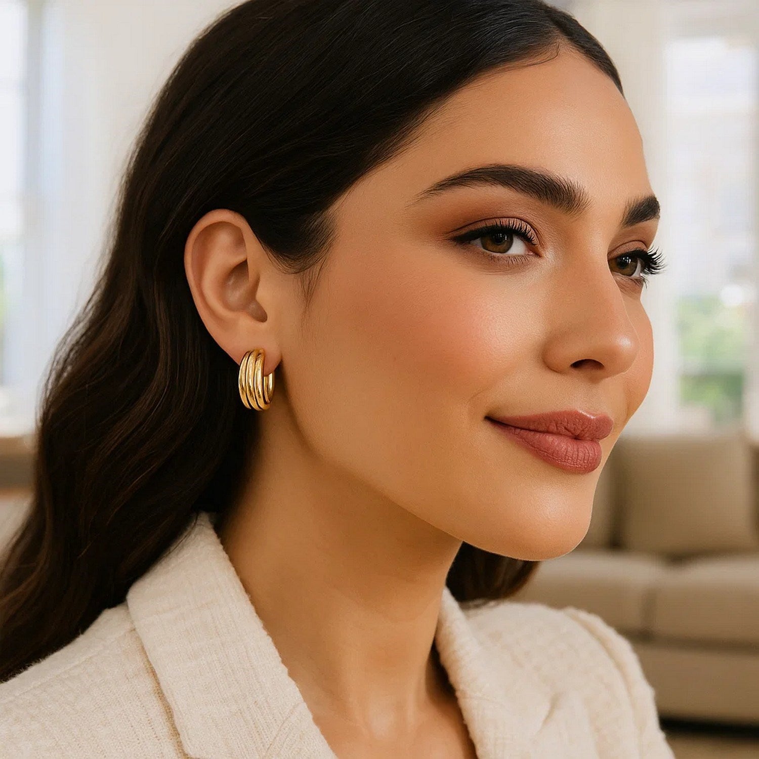 14K yellow gold ribbed hoop earrings are worn on a woman's ear.