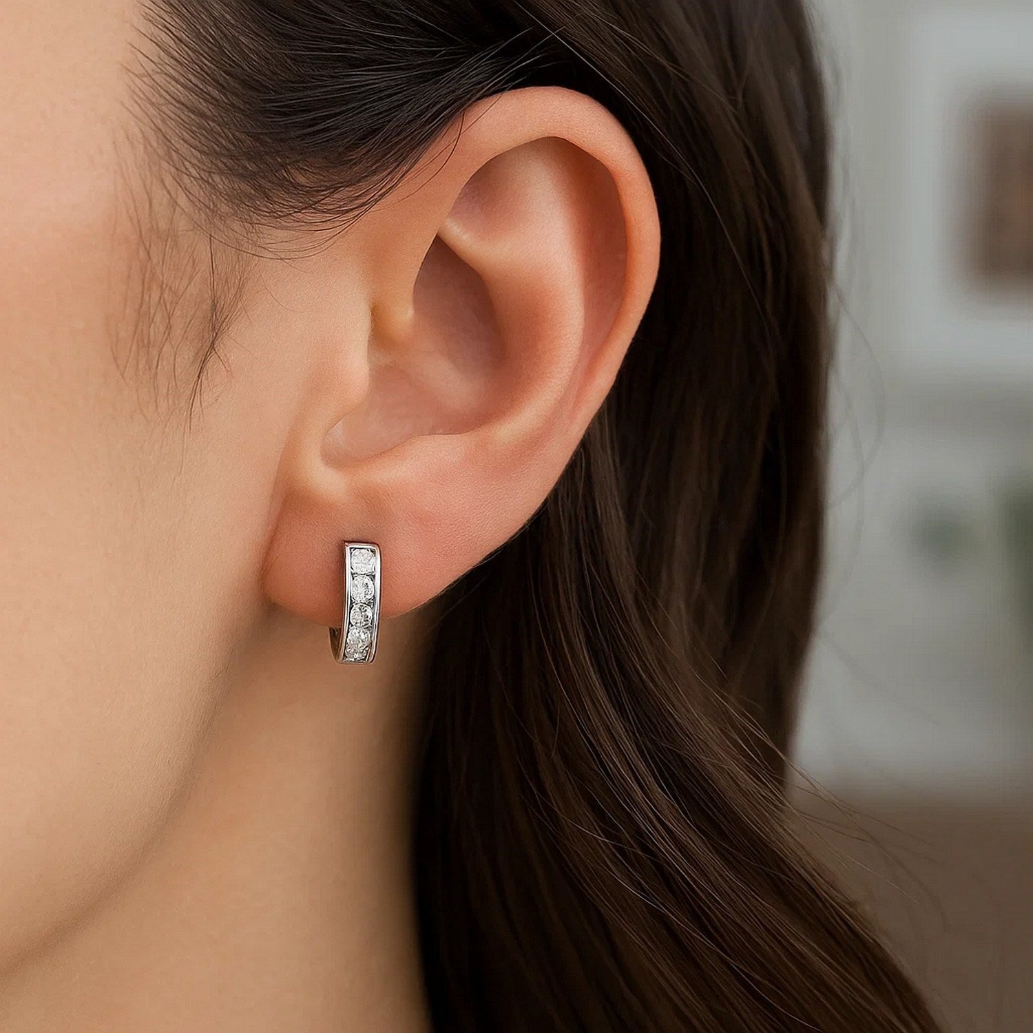 Sterling silver petite hoop earring with cubic zirconias on a woman's ear.